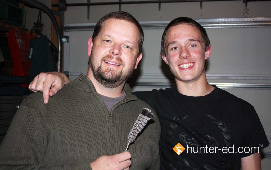 Hunter education instructor Randy Allen with his son and the grouse feather.