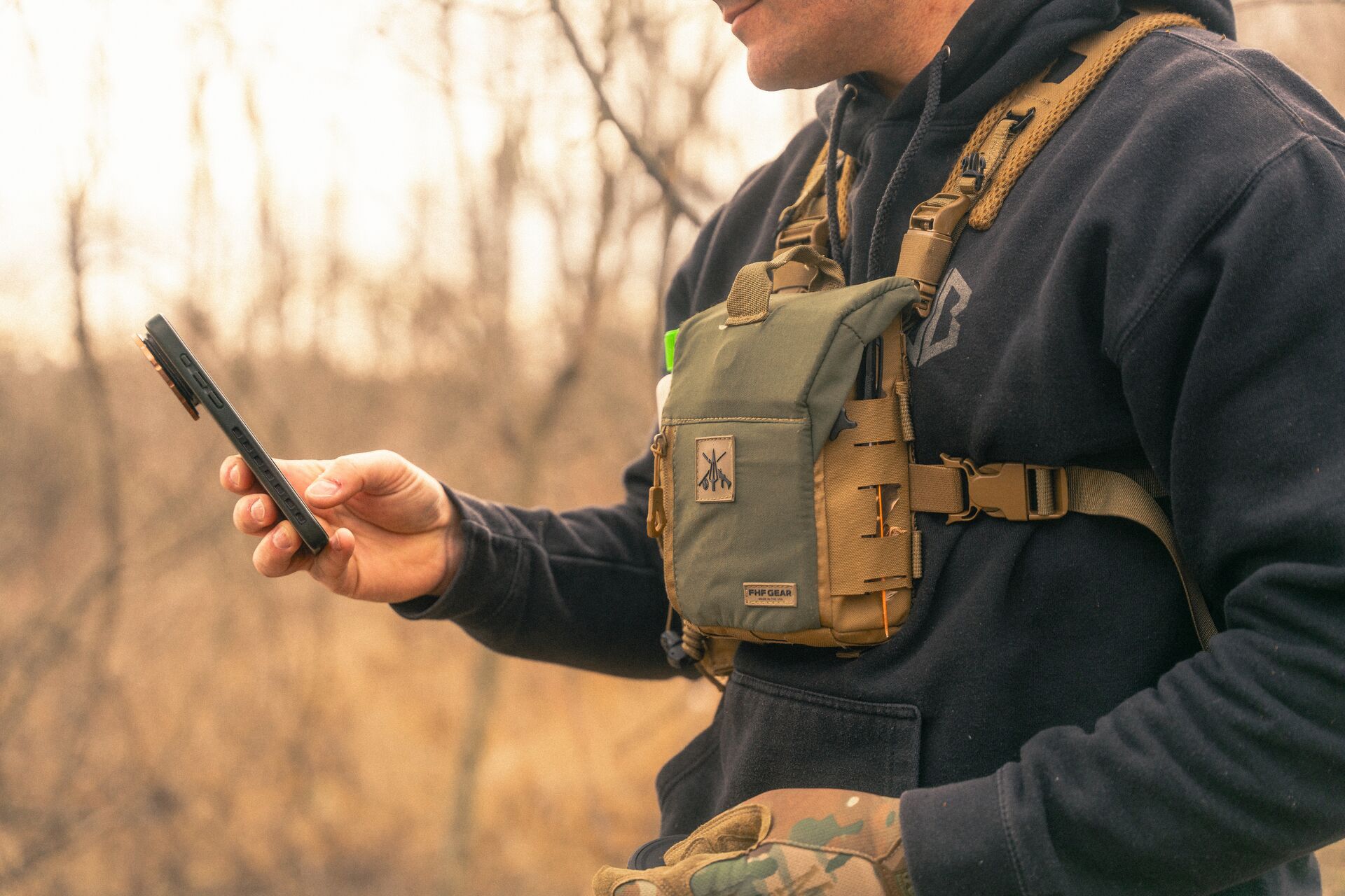 Hunter using cell phone in woods, more mushroom season concept.