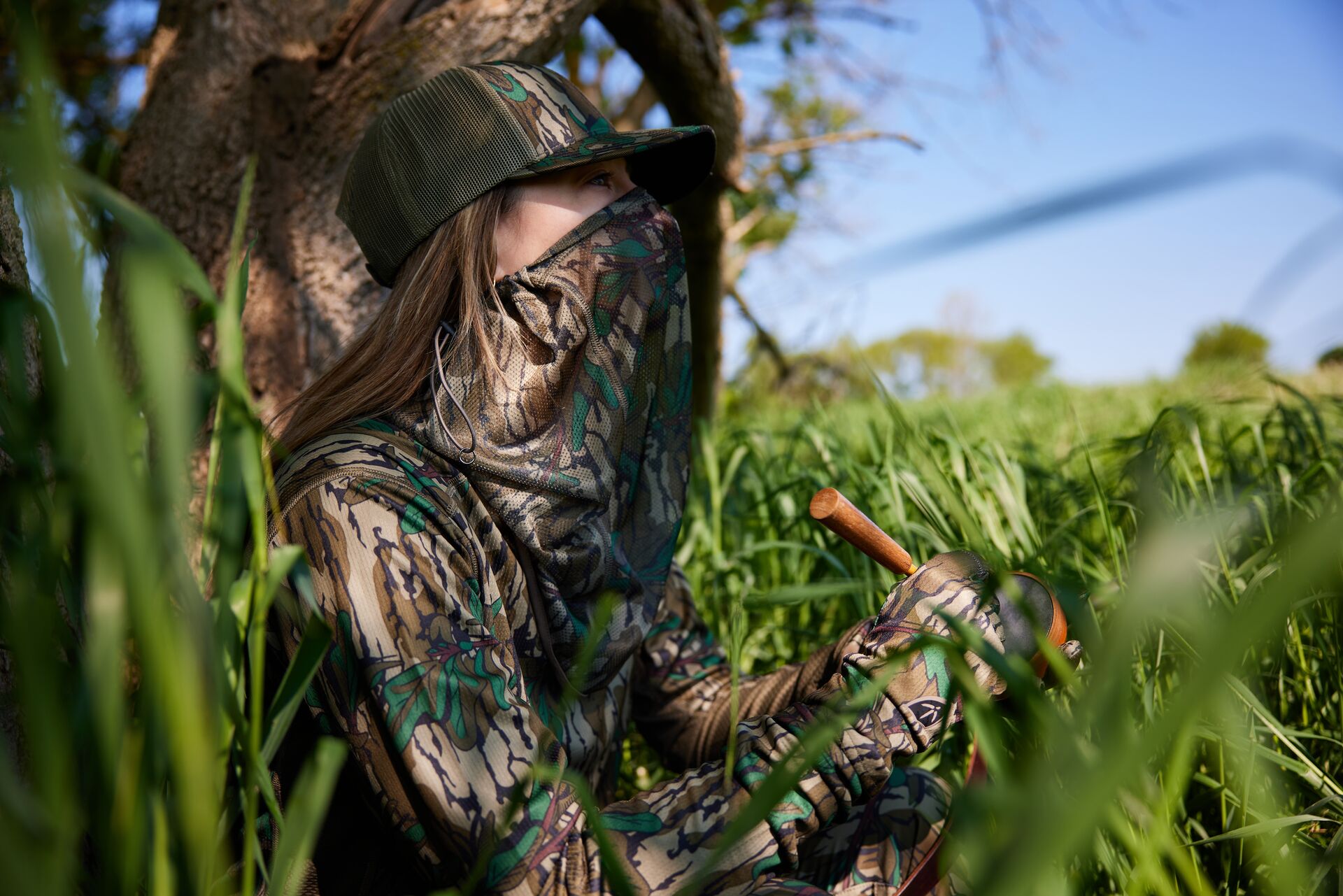 Female hunter uses turkey call in the brush, types of turkey calls concept. 