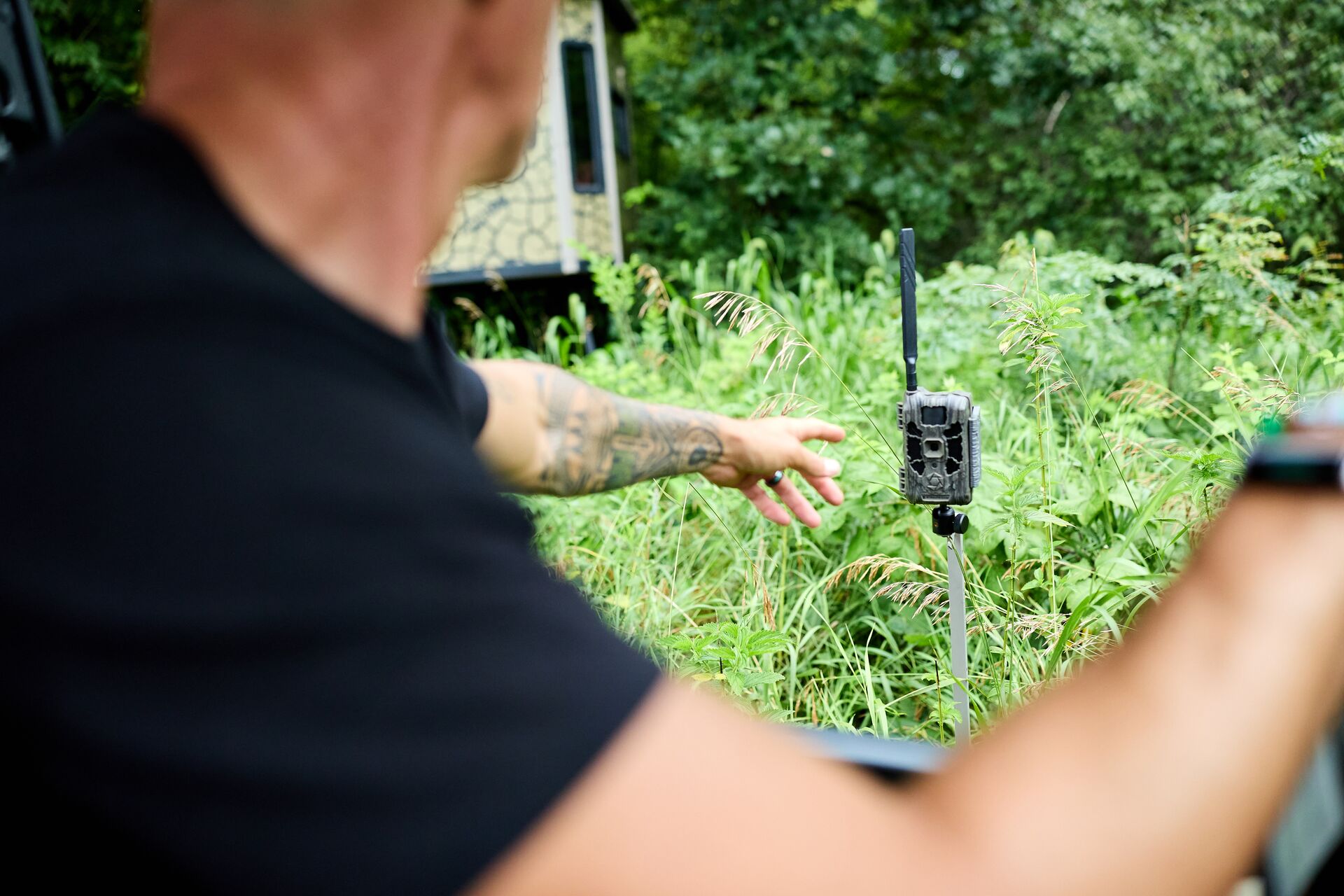 Hunter points at trail camera in a field, how does a cellular trail camera work concept.