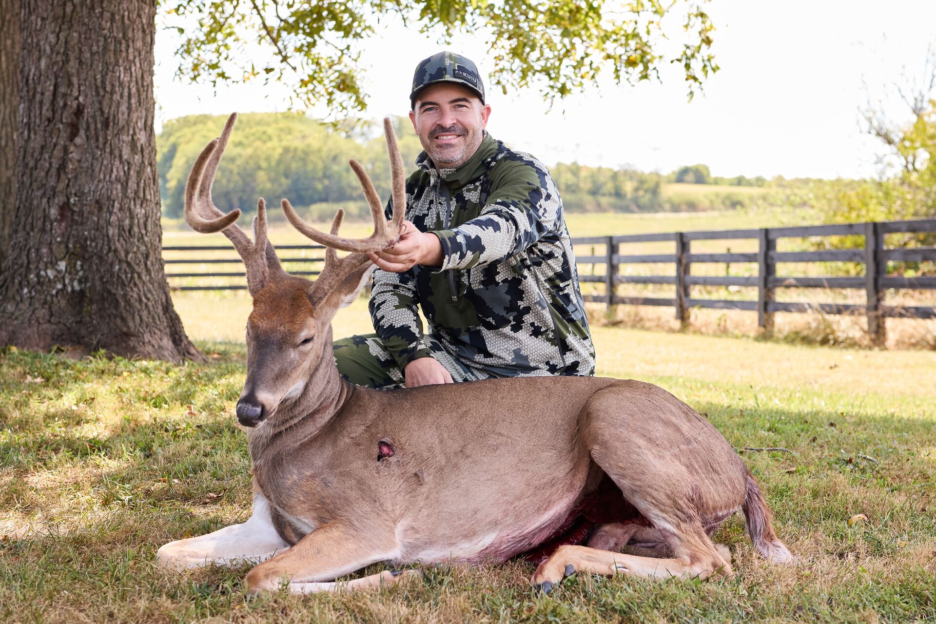 Hunter smiles with buck deer showing wound after hunt, understand deer anatomy concept.