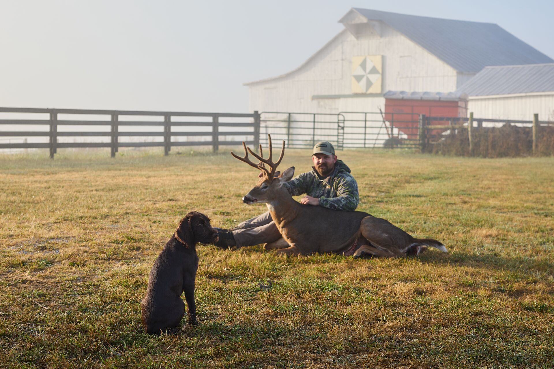 Hunter sits with buck deer after hunt, venison vs beef concept.