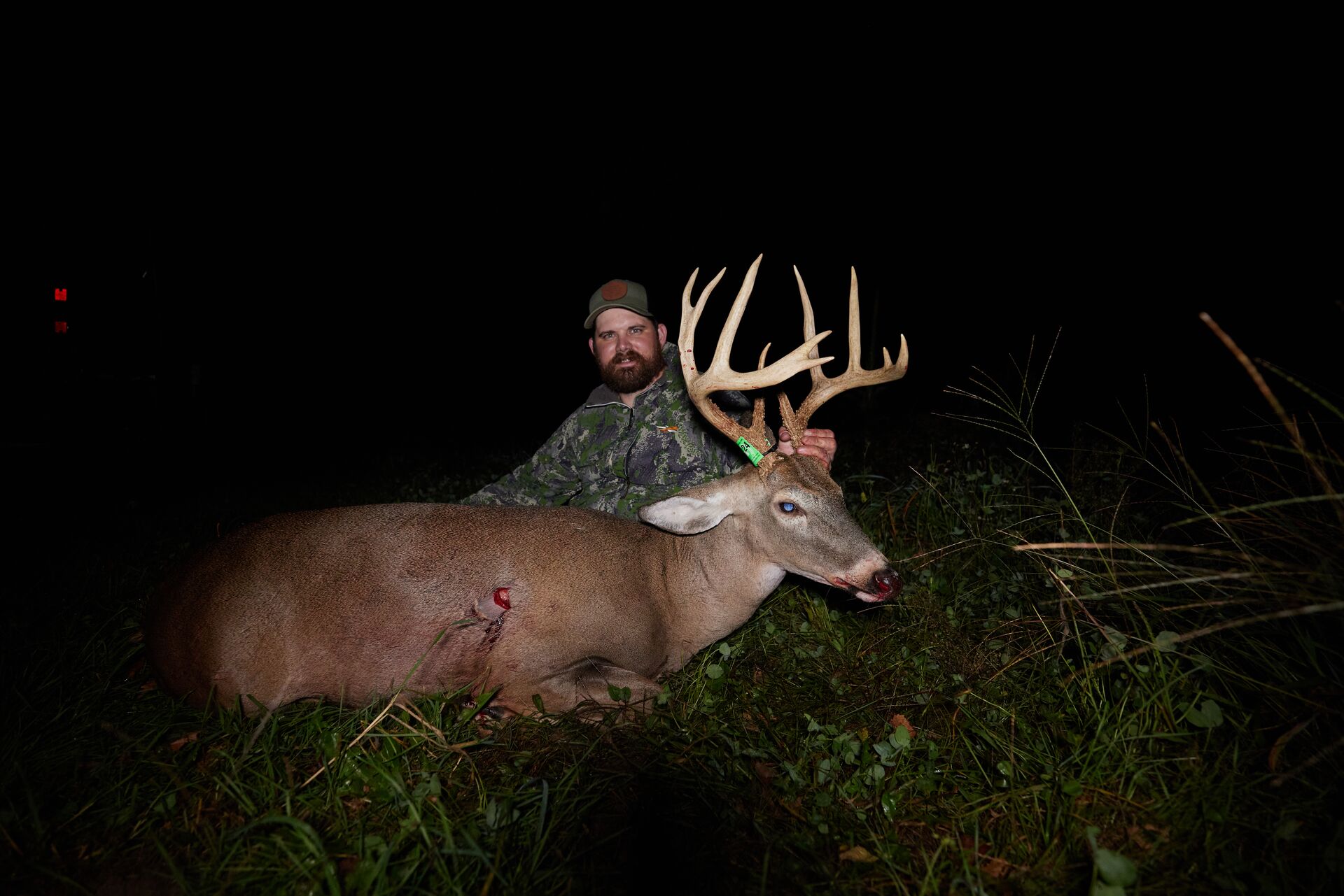 A hunter with a buck deer after a kill shot.
