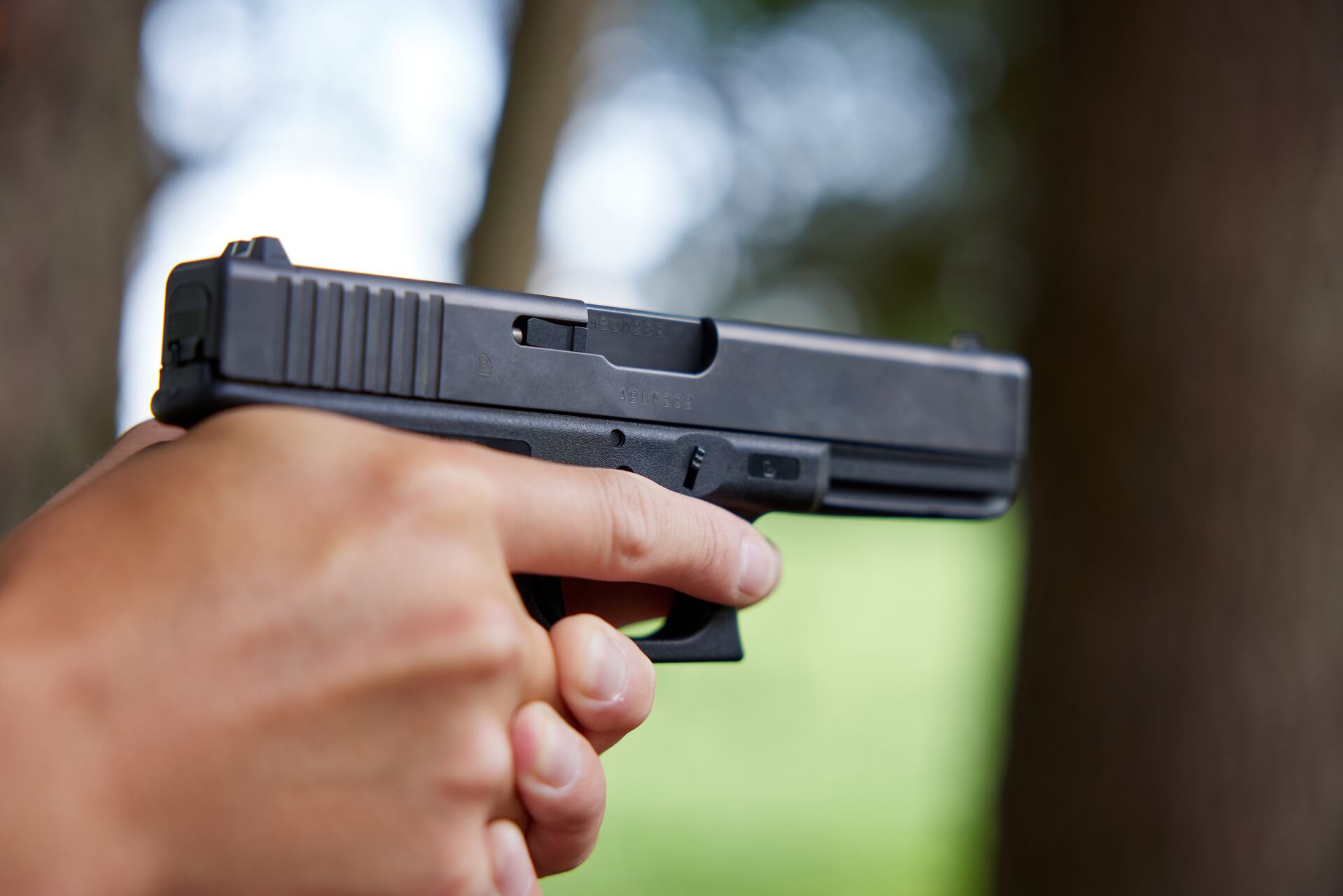 A close-up of a handgun in someone's hands aimed toward a target.