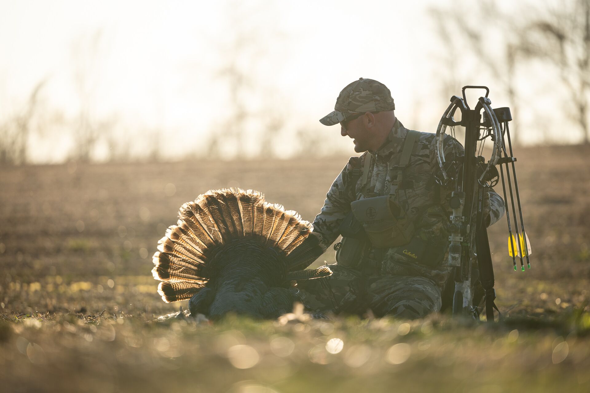 A hunter sits with a turkey and bow, how to turkey hunt for beginners concept.