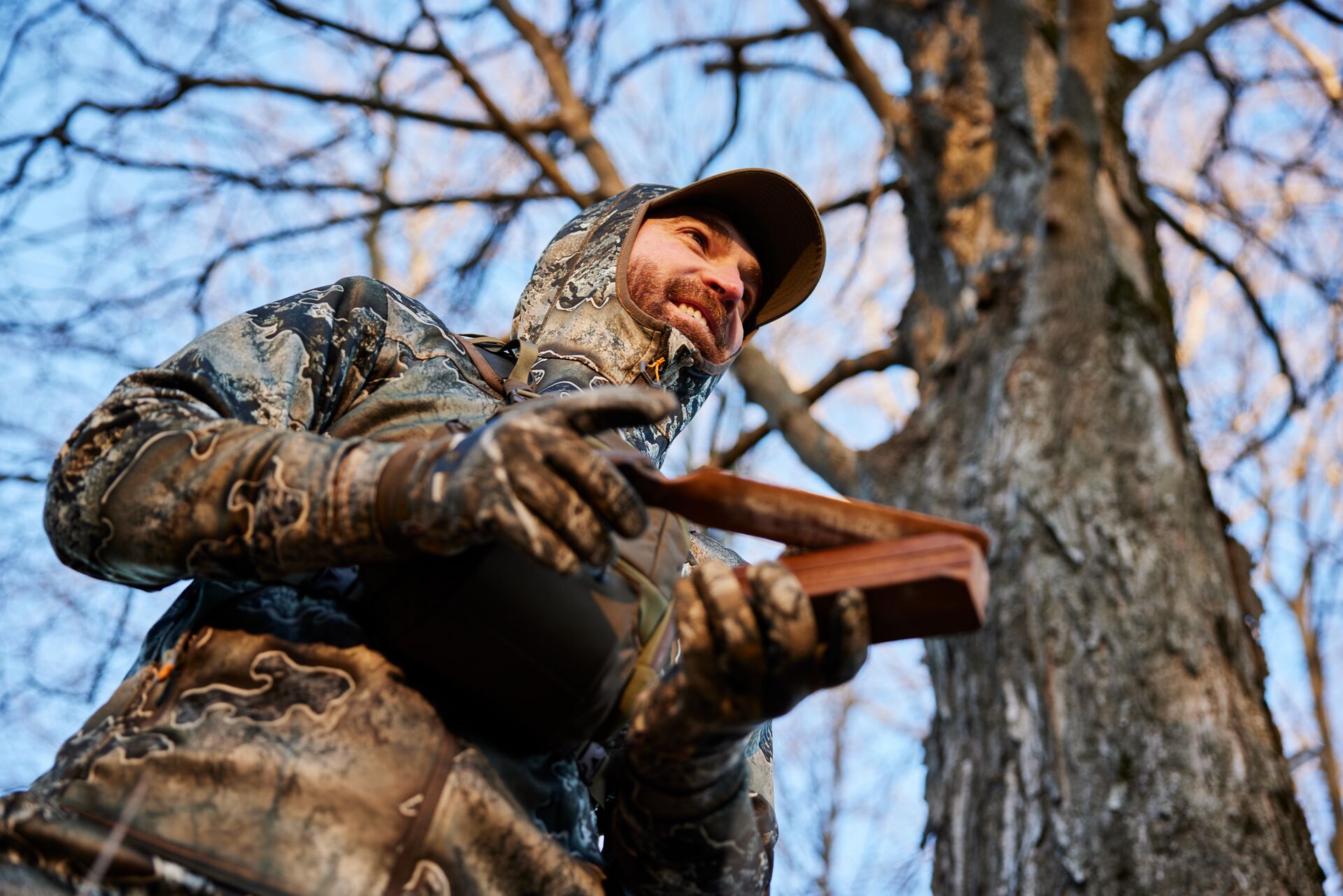 Hunter in camo uses turkey call, what do you need for turkey hunting concept.