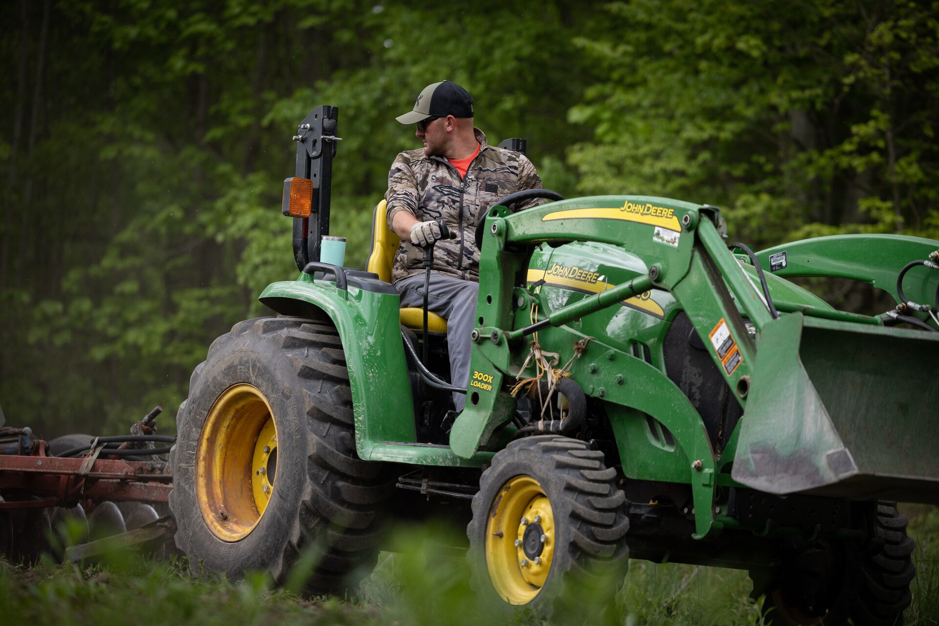 Hunter drives a tractor to prepare soil, when to plan deer food plots concept. 