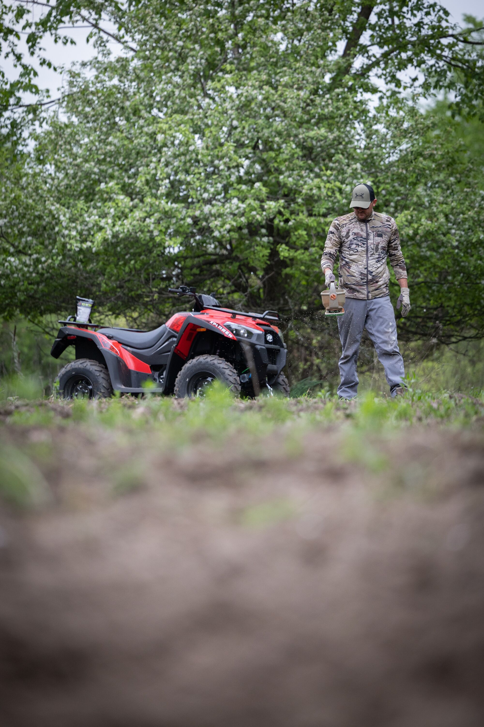 A hunter uses a hand spreader to seed a deer food plot. 