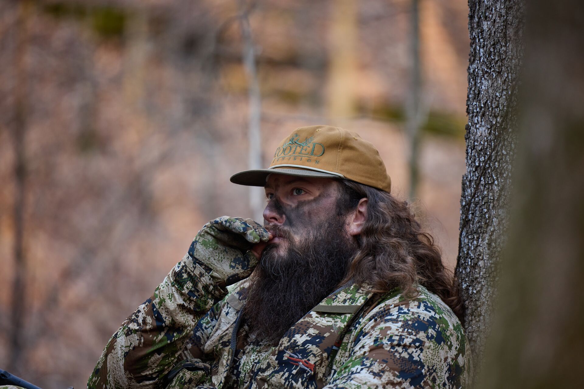RootedTV hunter using a turkey call in the woods. 