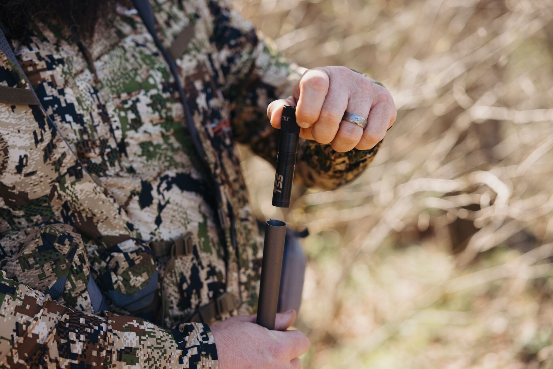 Close-up of a hunter adding a choke to the end of a shotgun.