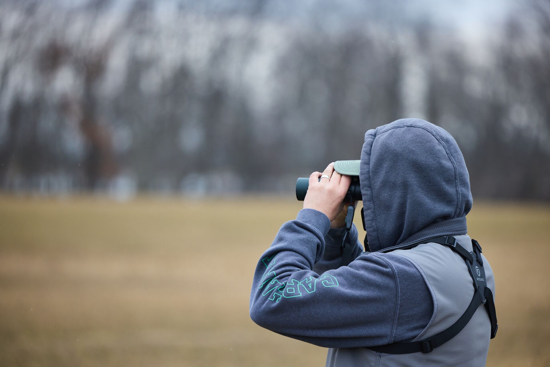 Person using binoculars to scout land. 