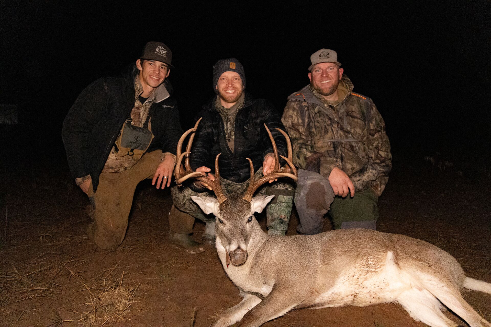 Three hunters pose with a buck deer after a hunt. 