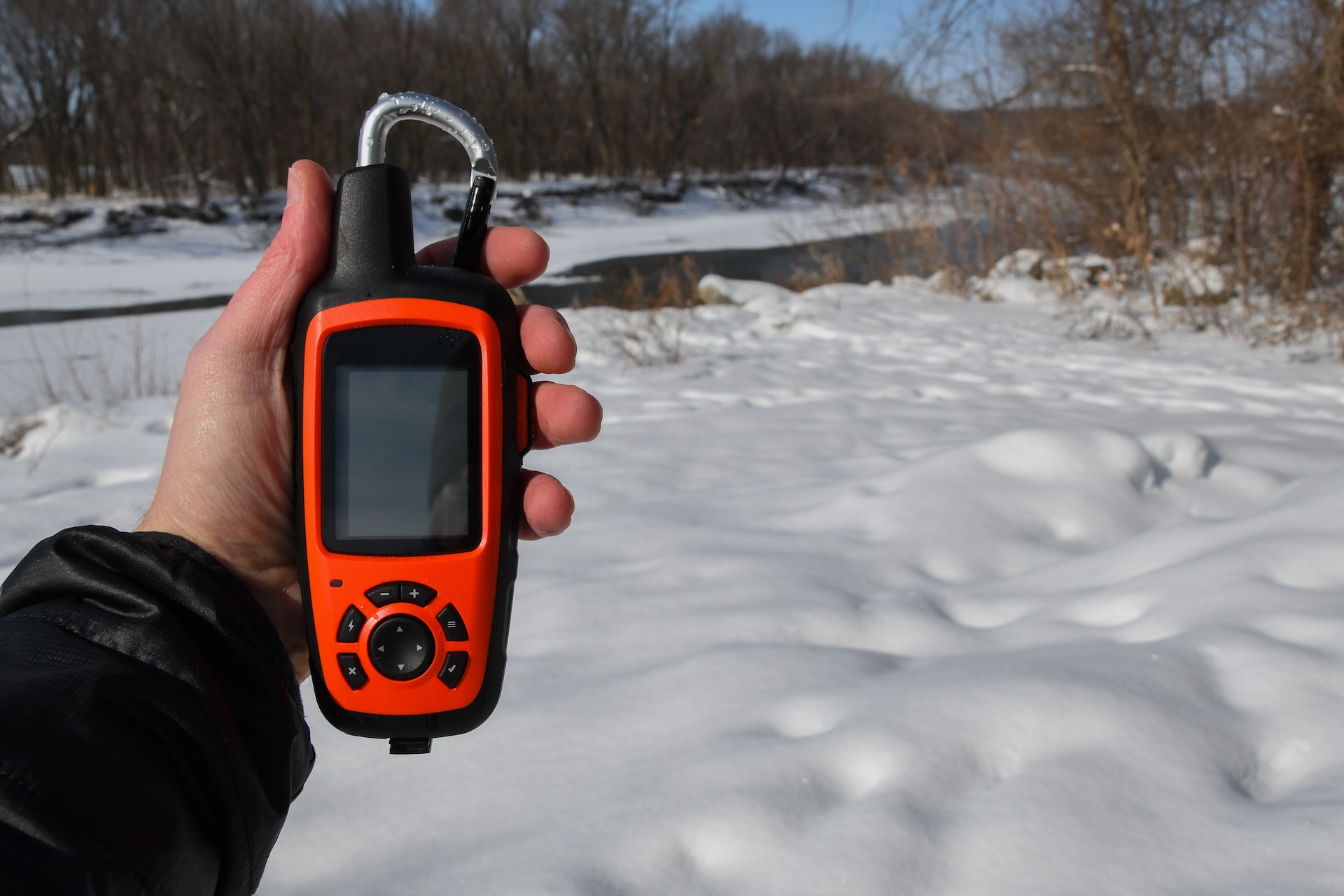 Close-up of a GPS tools in someone's hand while in the snowy woods. 