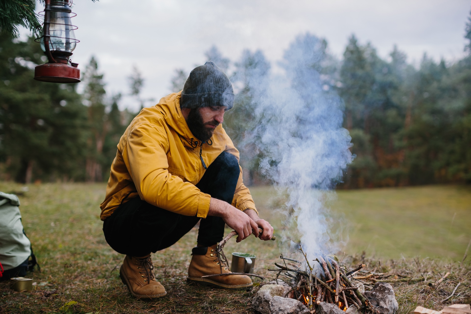 A man builds a campfire in the woods, hunting and outdoor survival skills concept. 