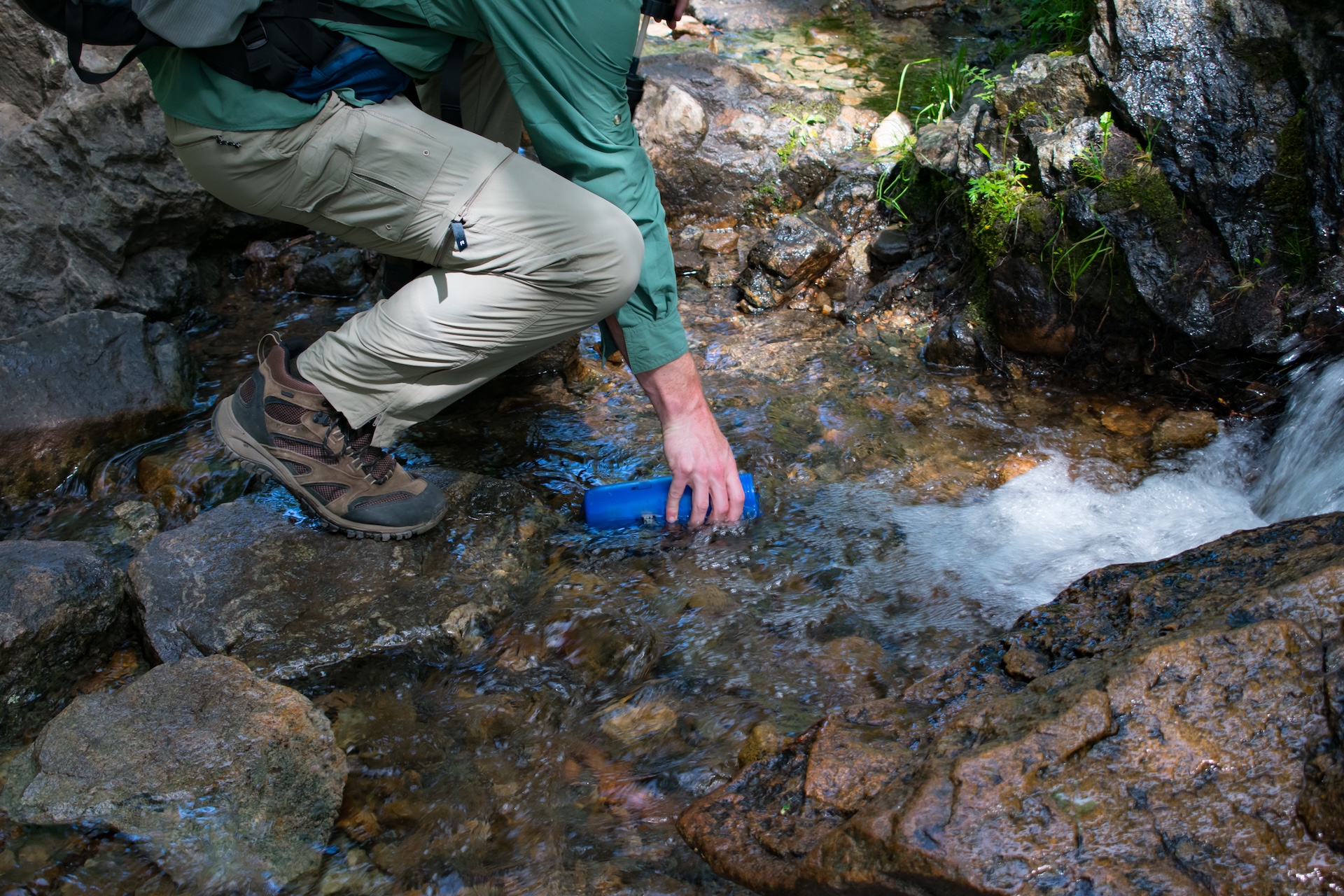 A person gets water from a stream, hunting and outdoor survival skills concept. 