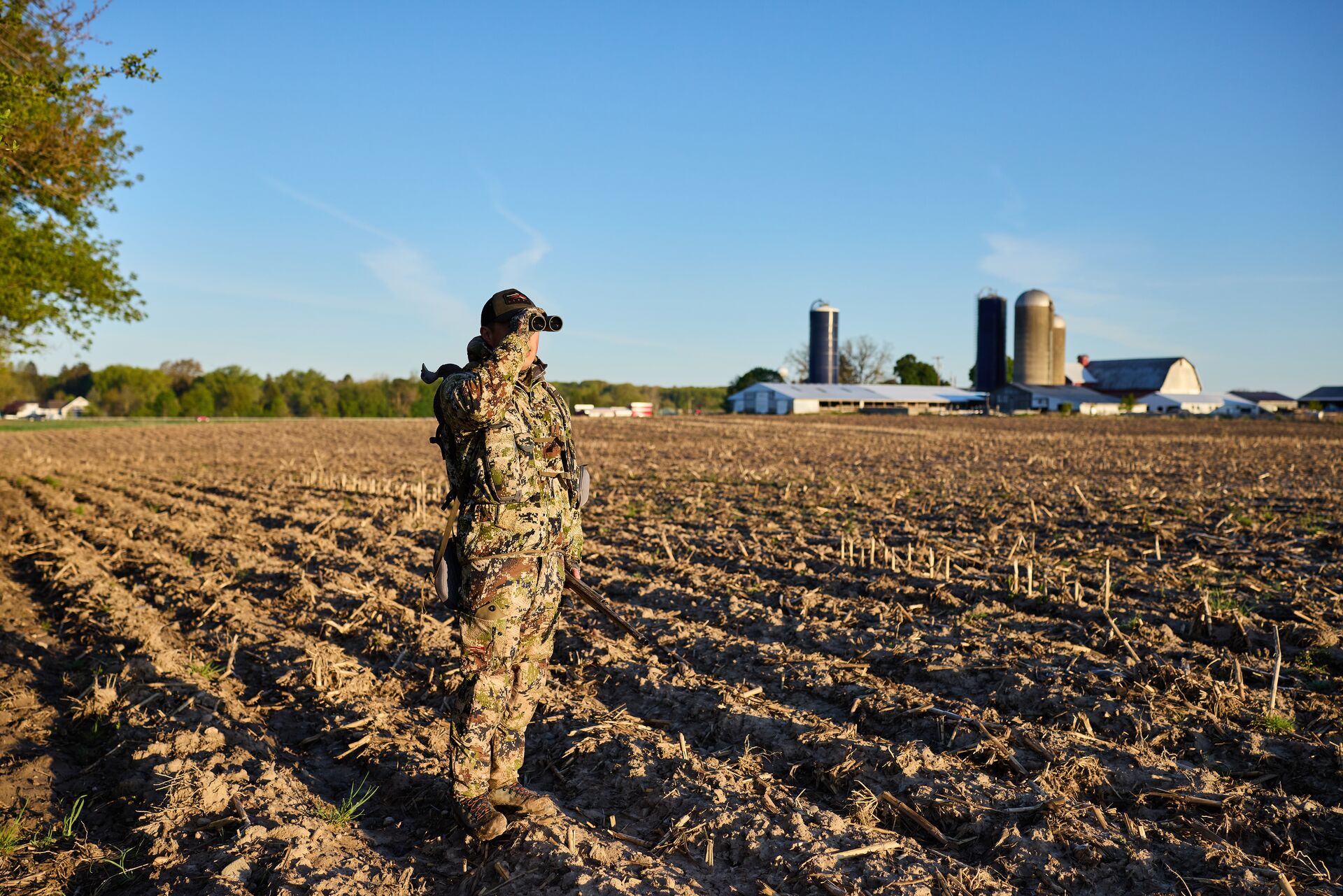 Hunter in an ag field using binoculars, what is a hunting lease concept.