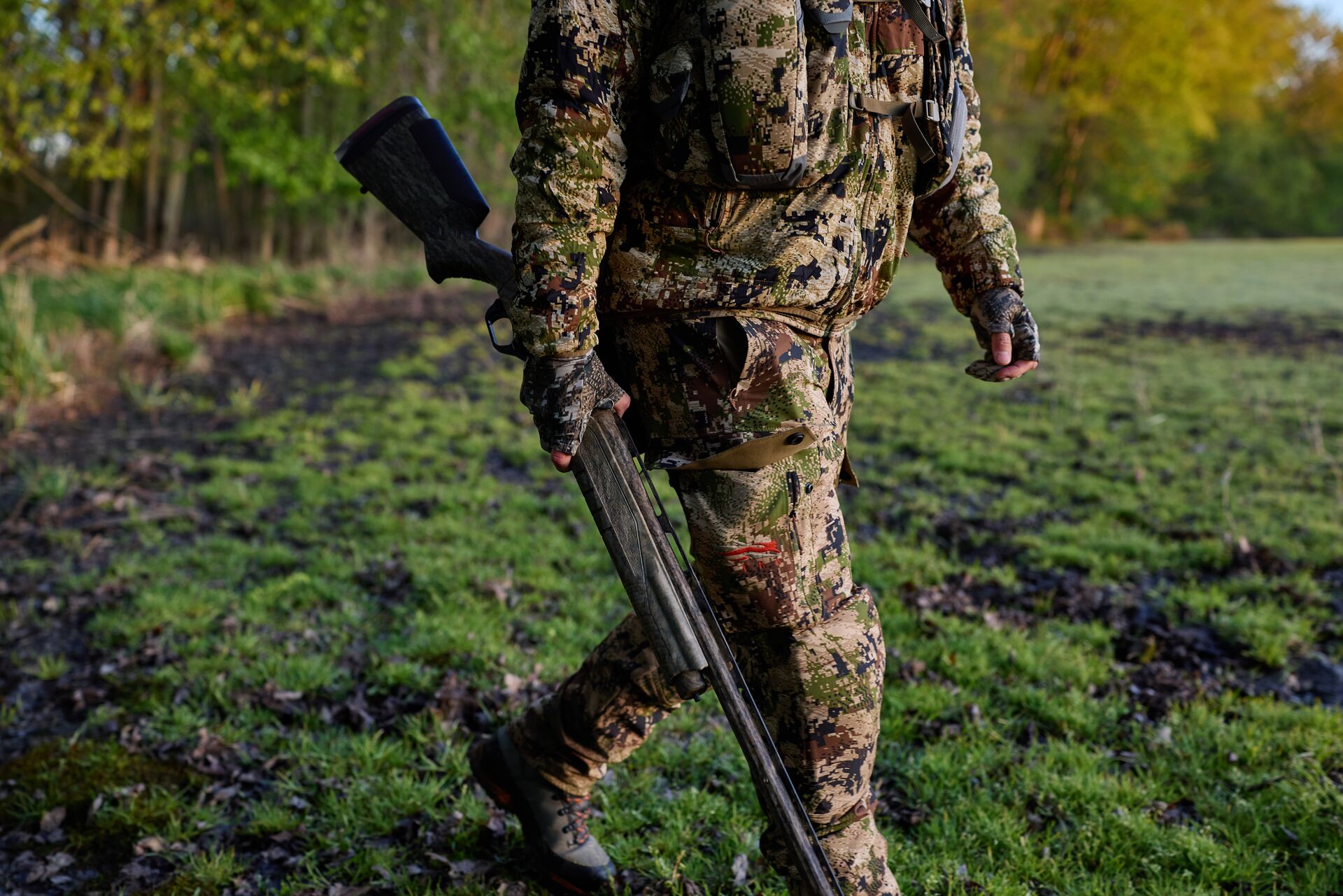 Hunter in camo walks with shotgun, what can you hunt in summer concept.