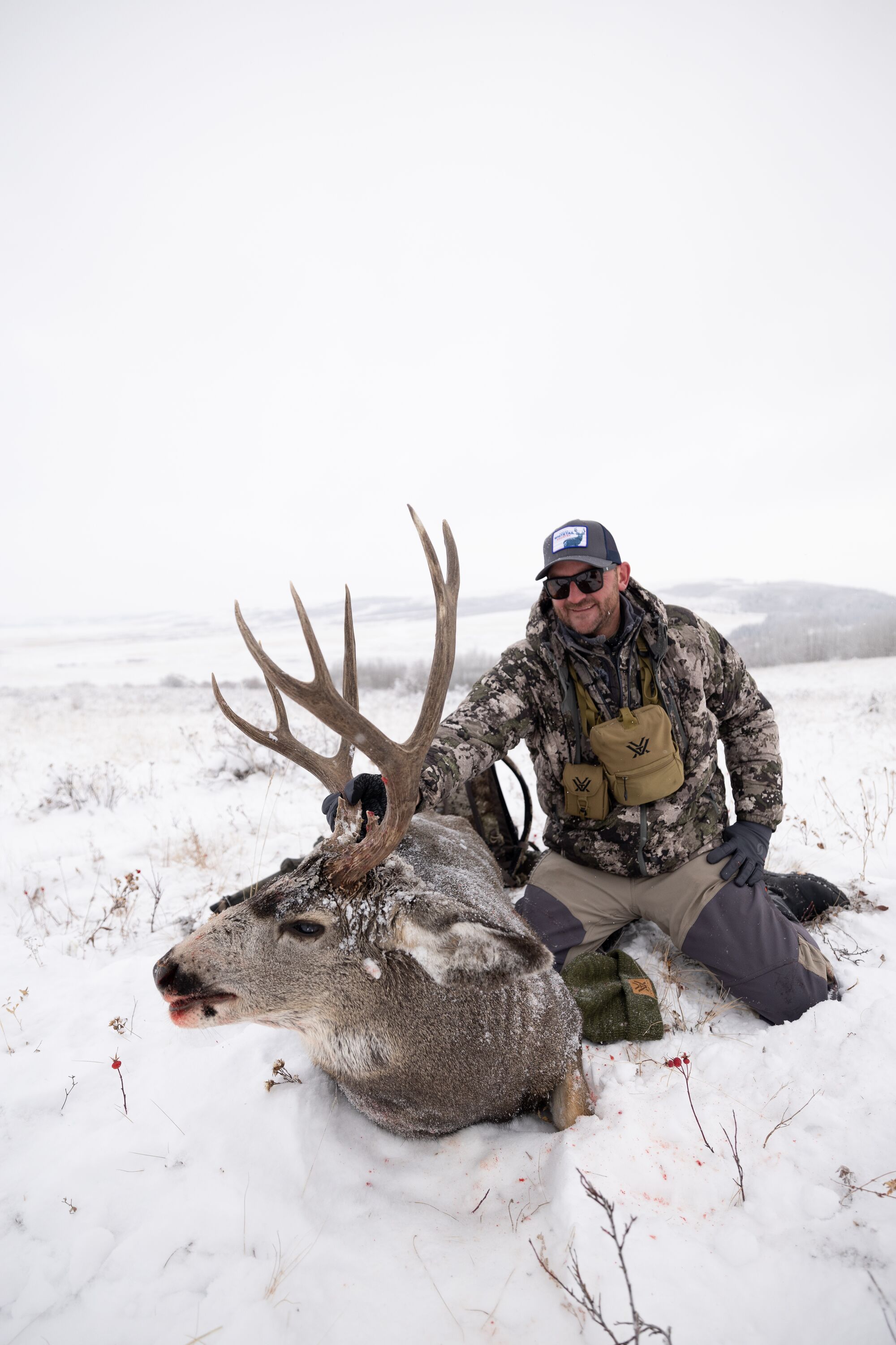 Hunter poses with buck in the snow after hunt, beginner hunting tips concept. 