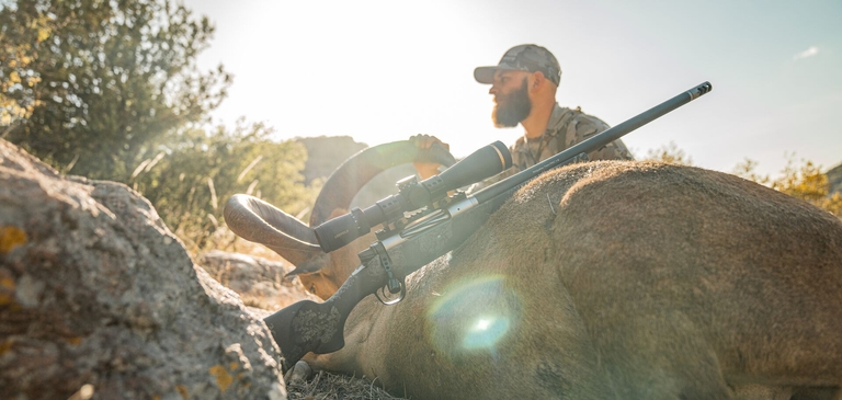 Hunter with big game rifle and ram after hunt, using big game cartridges concept. 