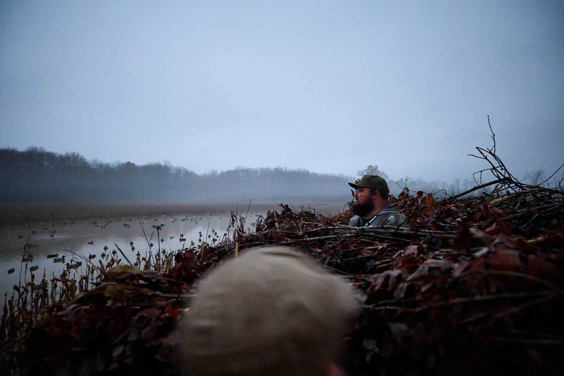 Hunter looks out over a duck hunting blind, how to set up duck decoys concept. 