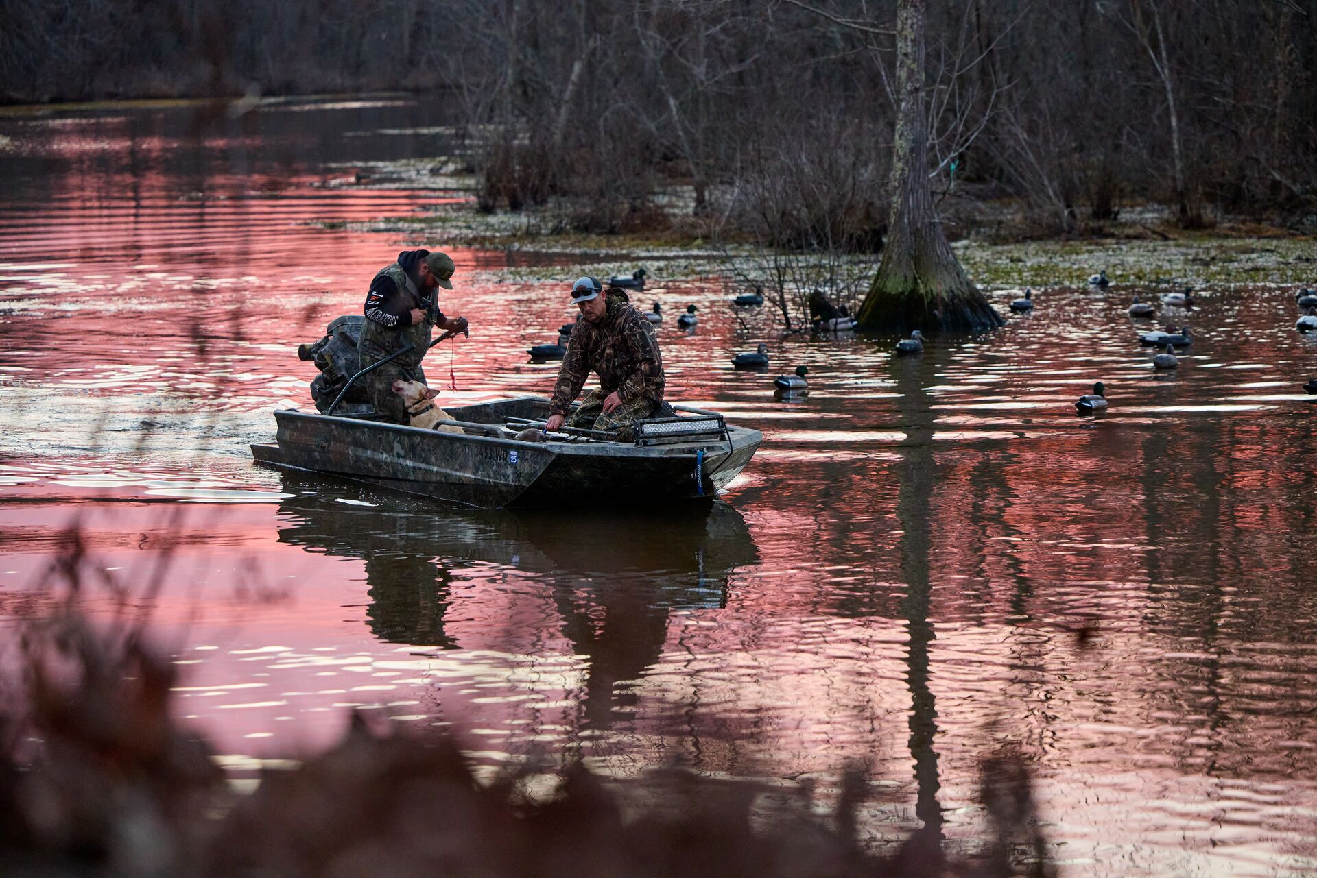 Hunters in a boat set up duck decoys, how to setup duck decoys concept. 
