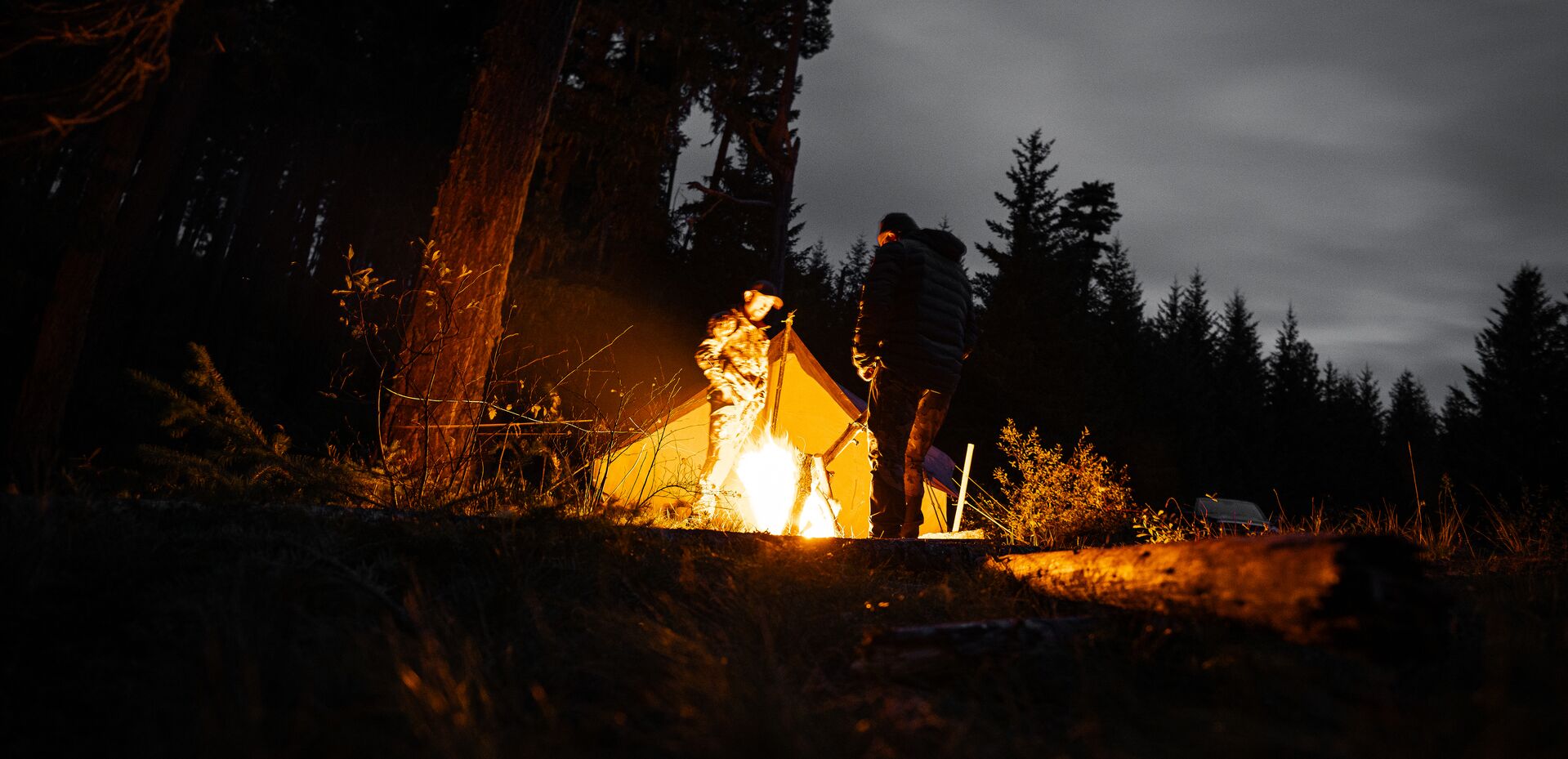 Hunters at tent with campfire, have a hunting survival kit concept. 