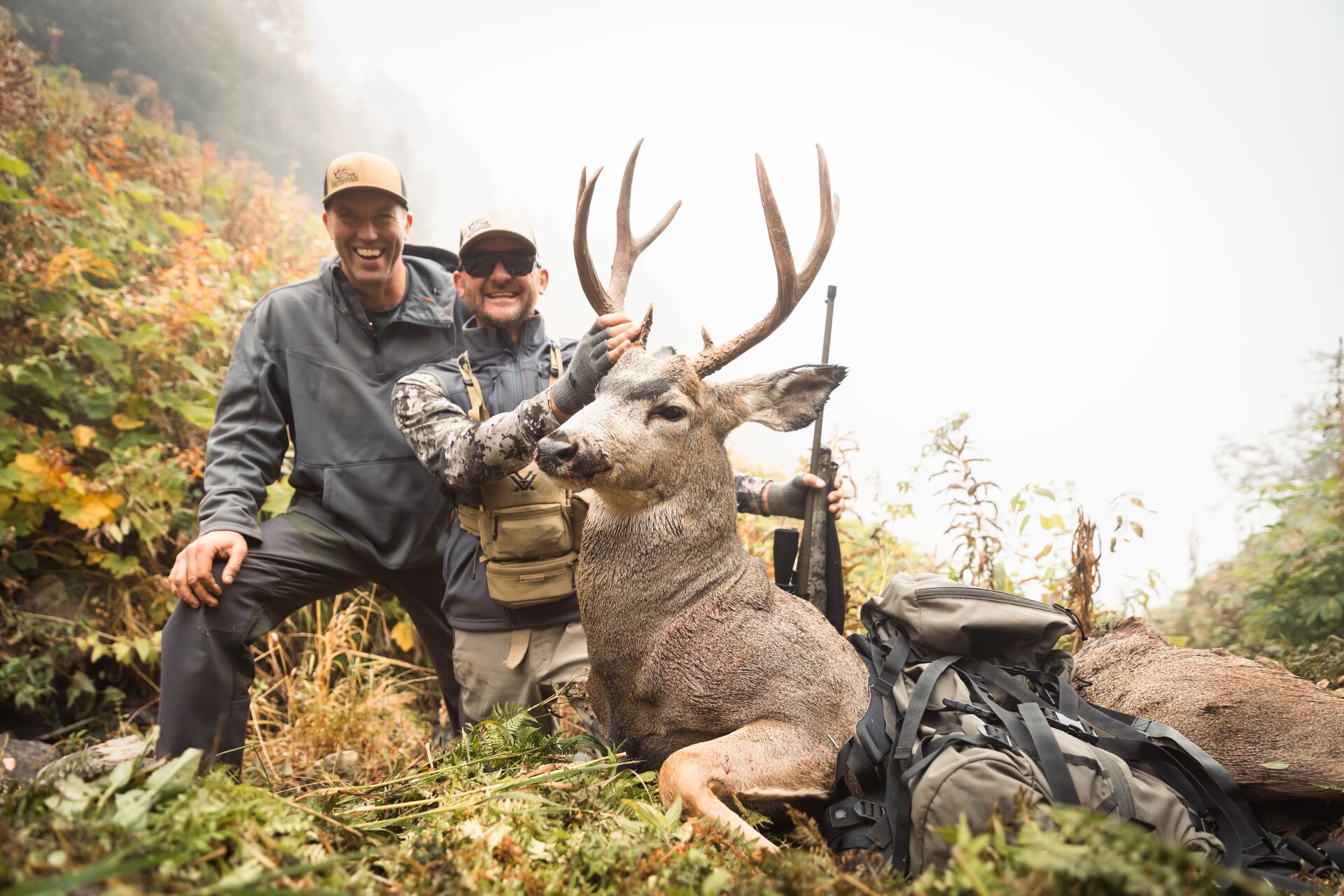 Two smiling hunters with large buck deer after hunt. 