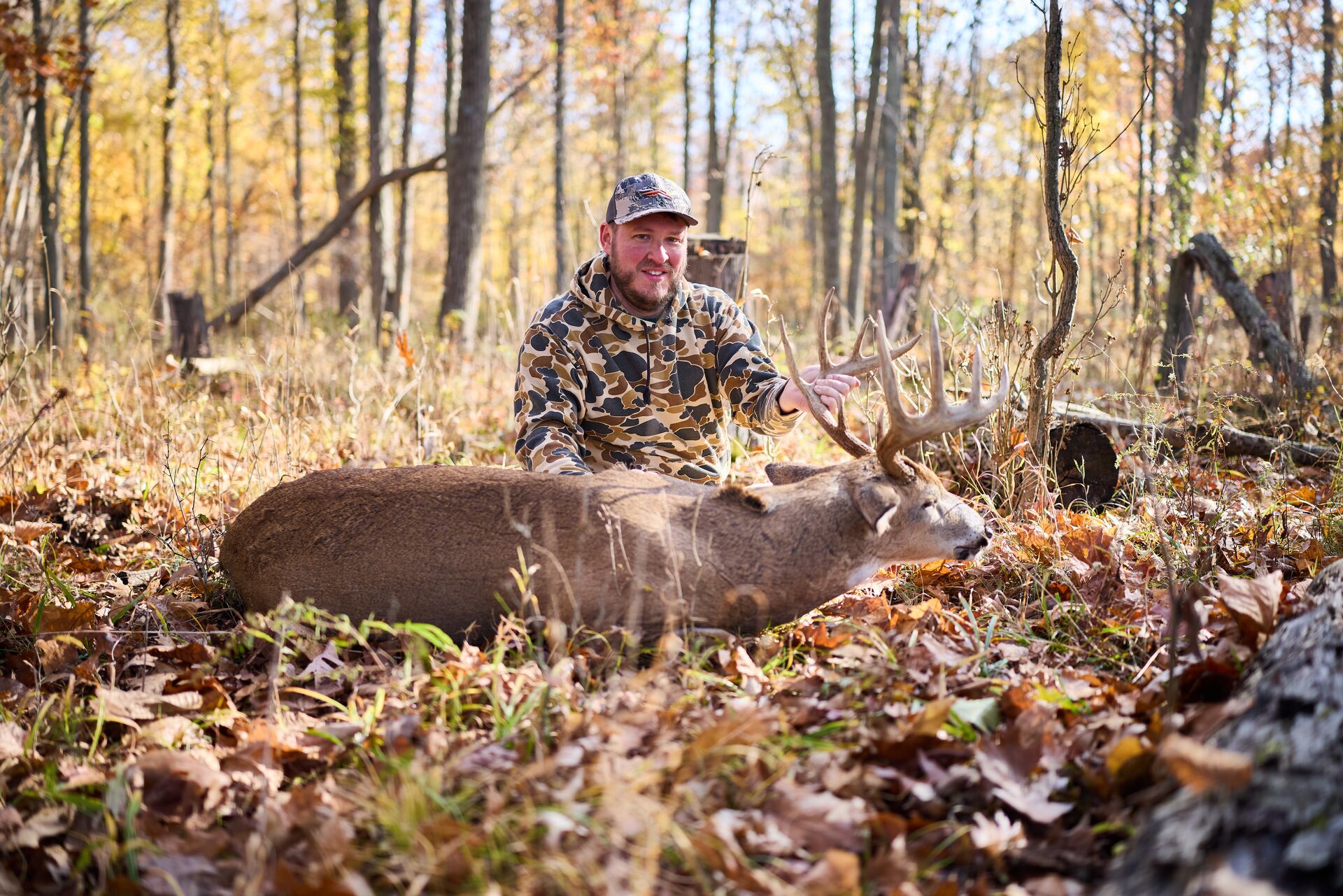 Smiling hunter with buck deer on ground after hunt, hunting for beginners concept. 