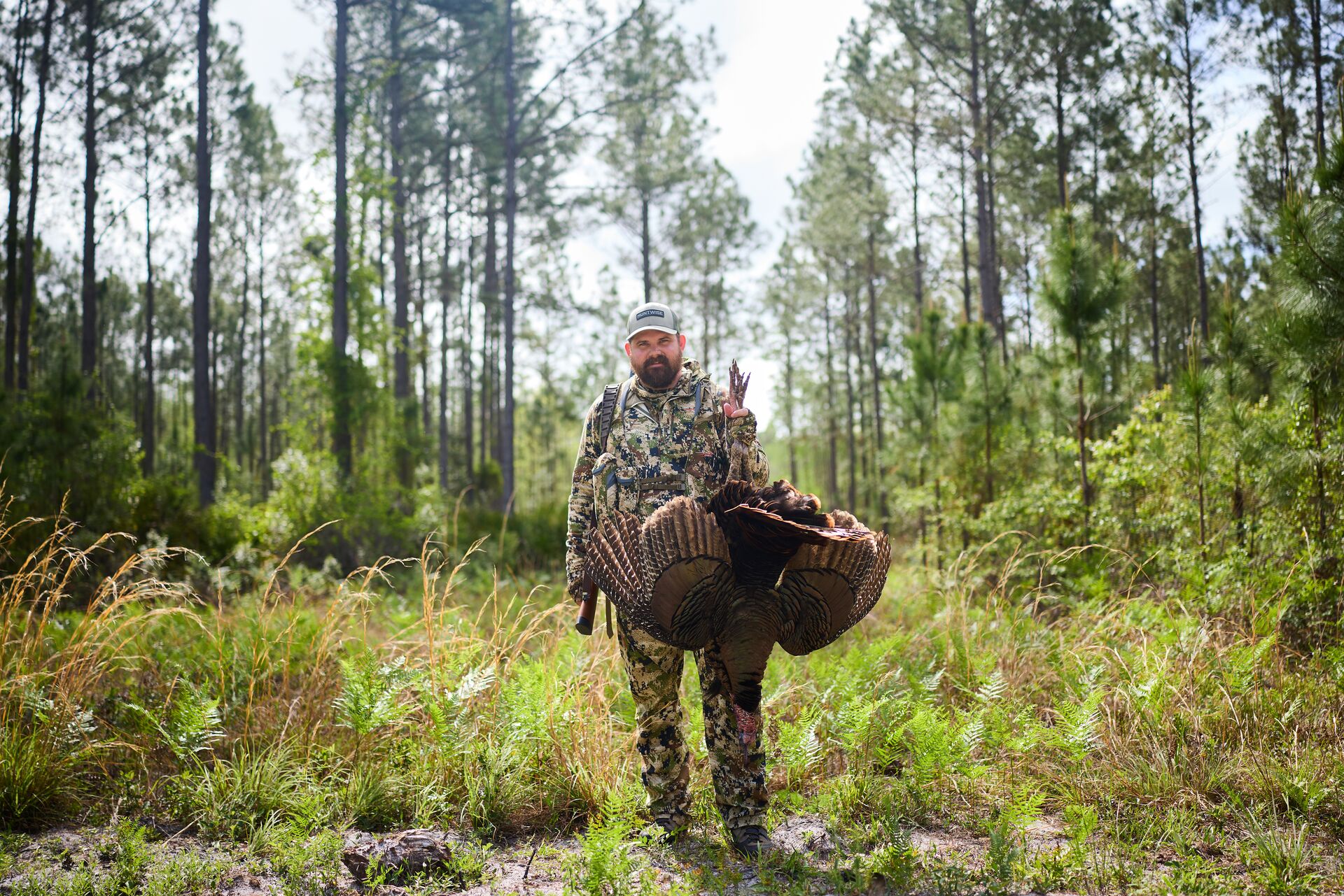 Hunter stands while holding a turkey after a turkey hunt, turkey hunting safety concept. 
