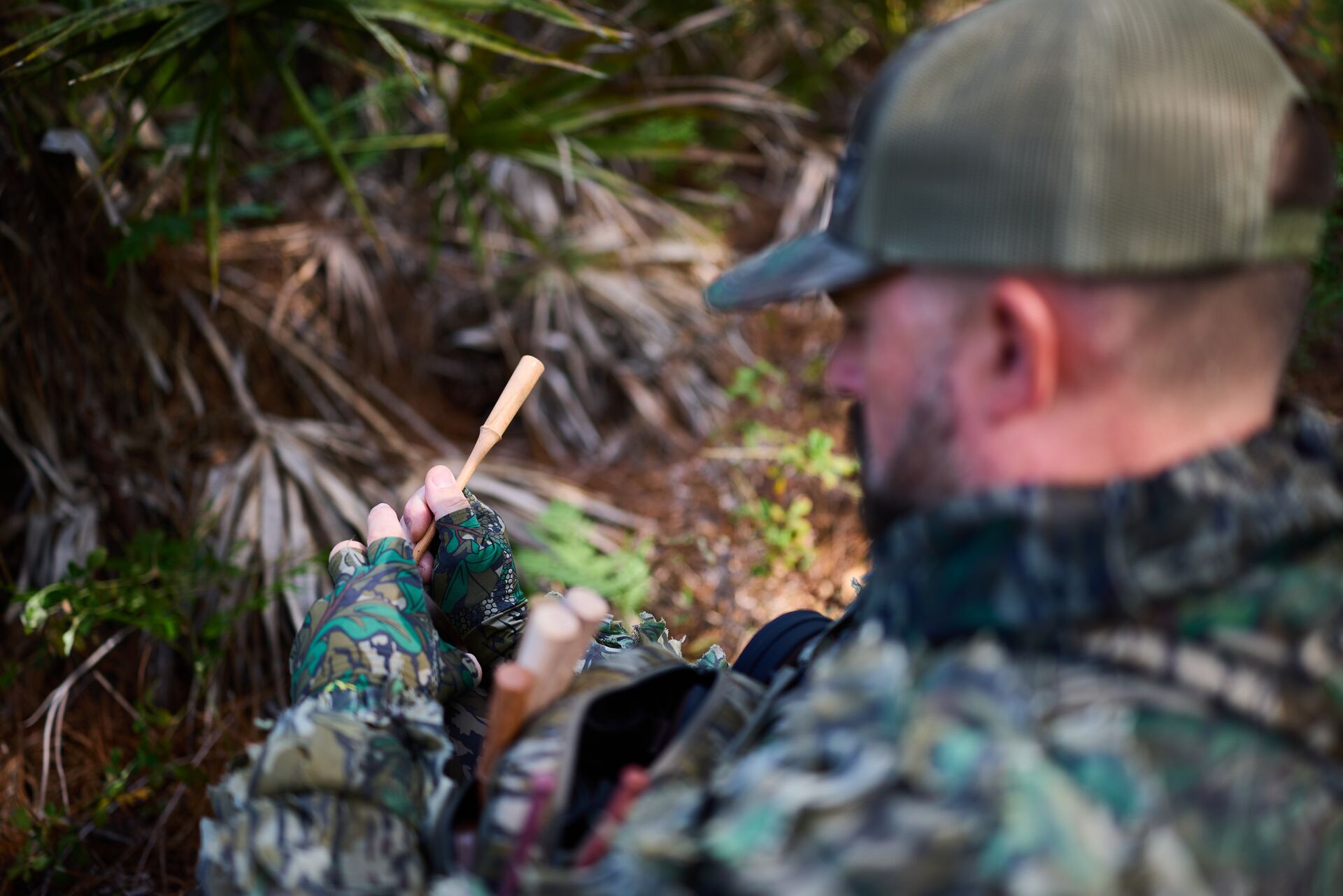 Hunter uses a turkey call in the woods. 