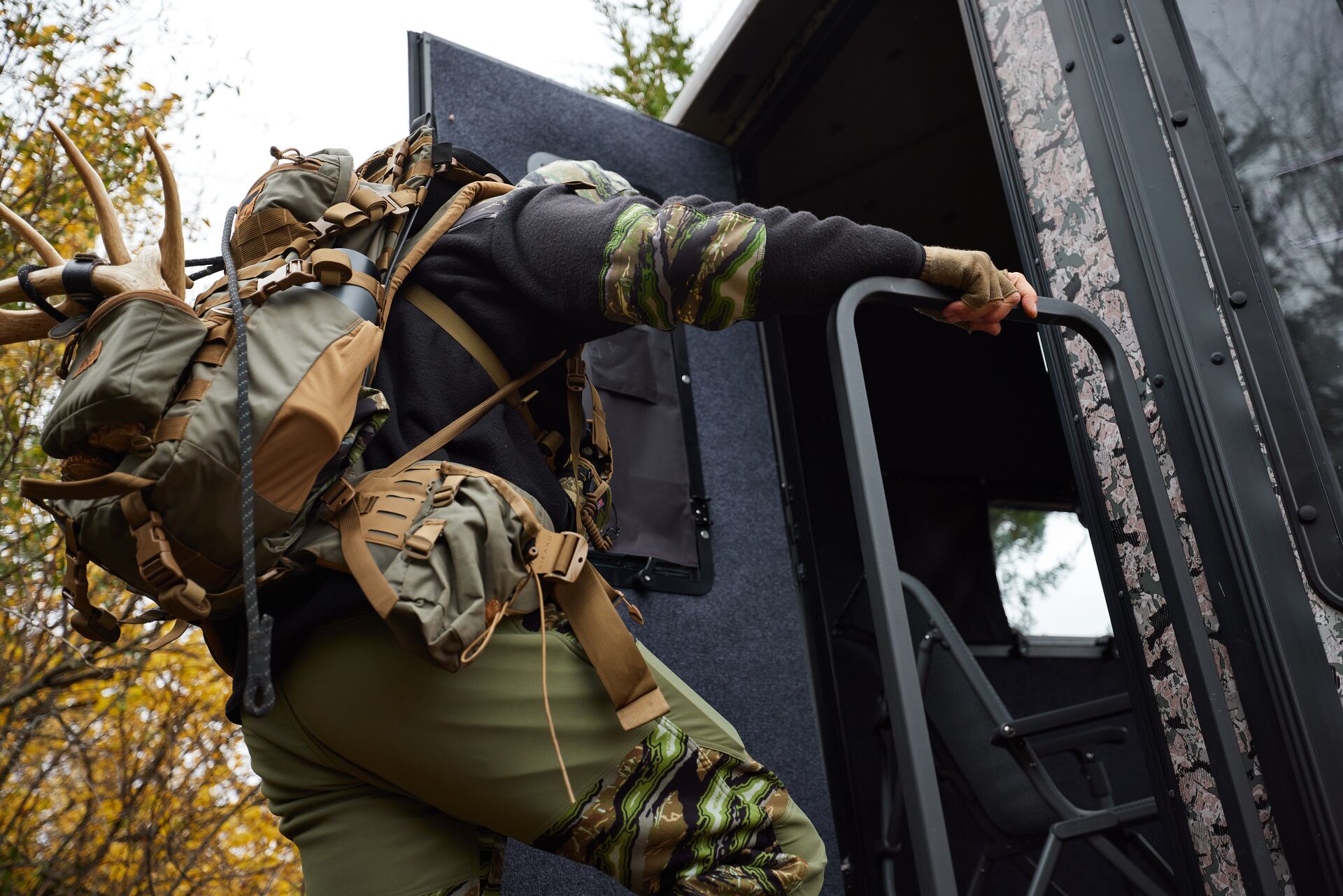 Hunter with gear climbs into ladder stand, hunting trip checklist concept.