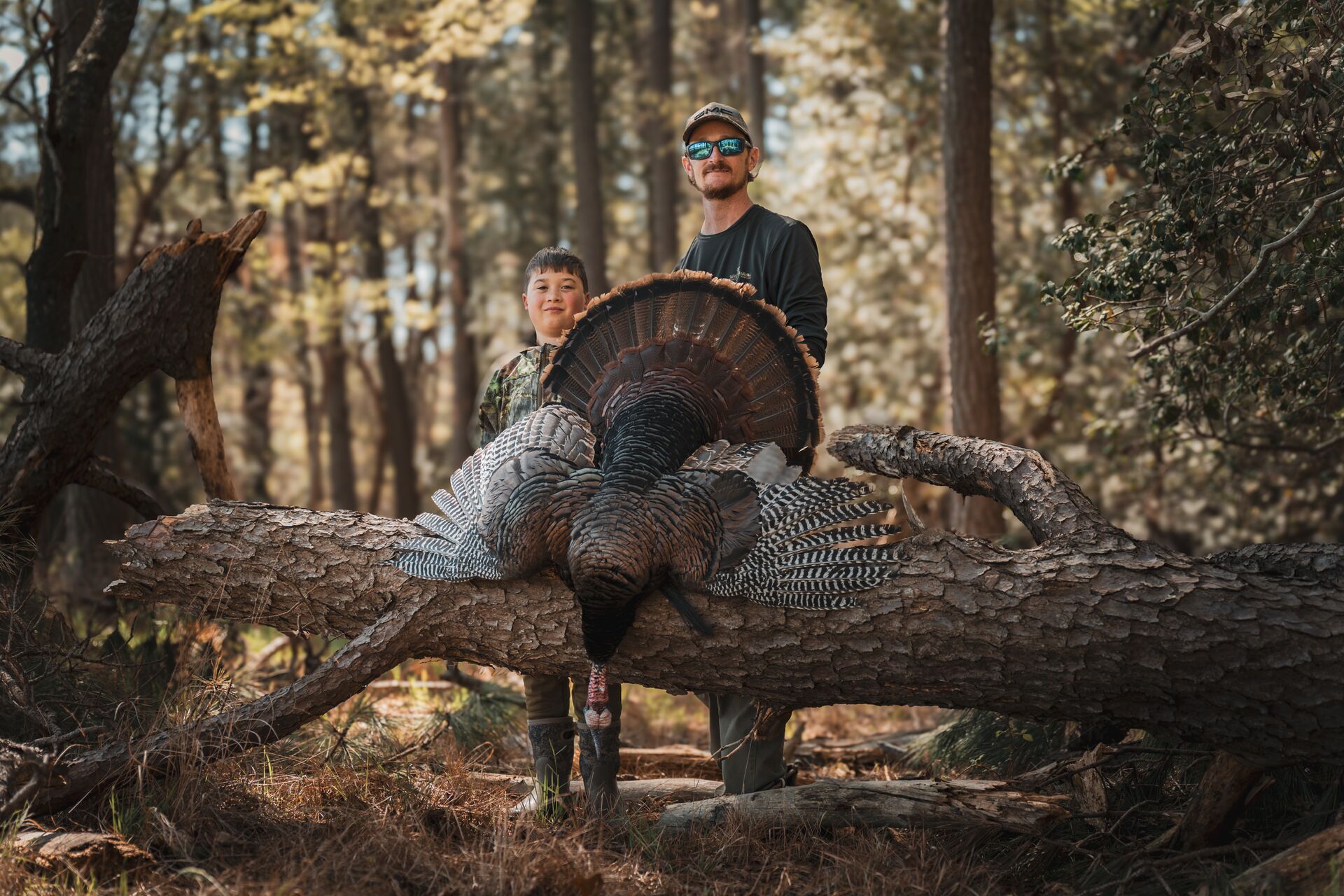Man and boy pose behind turkey after hunt, get a Texas hunting license concept.