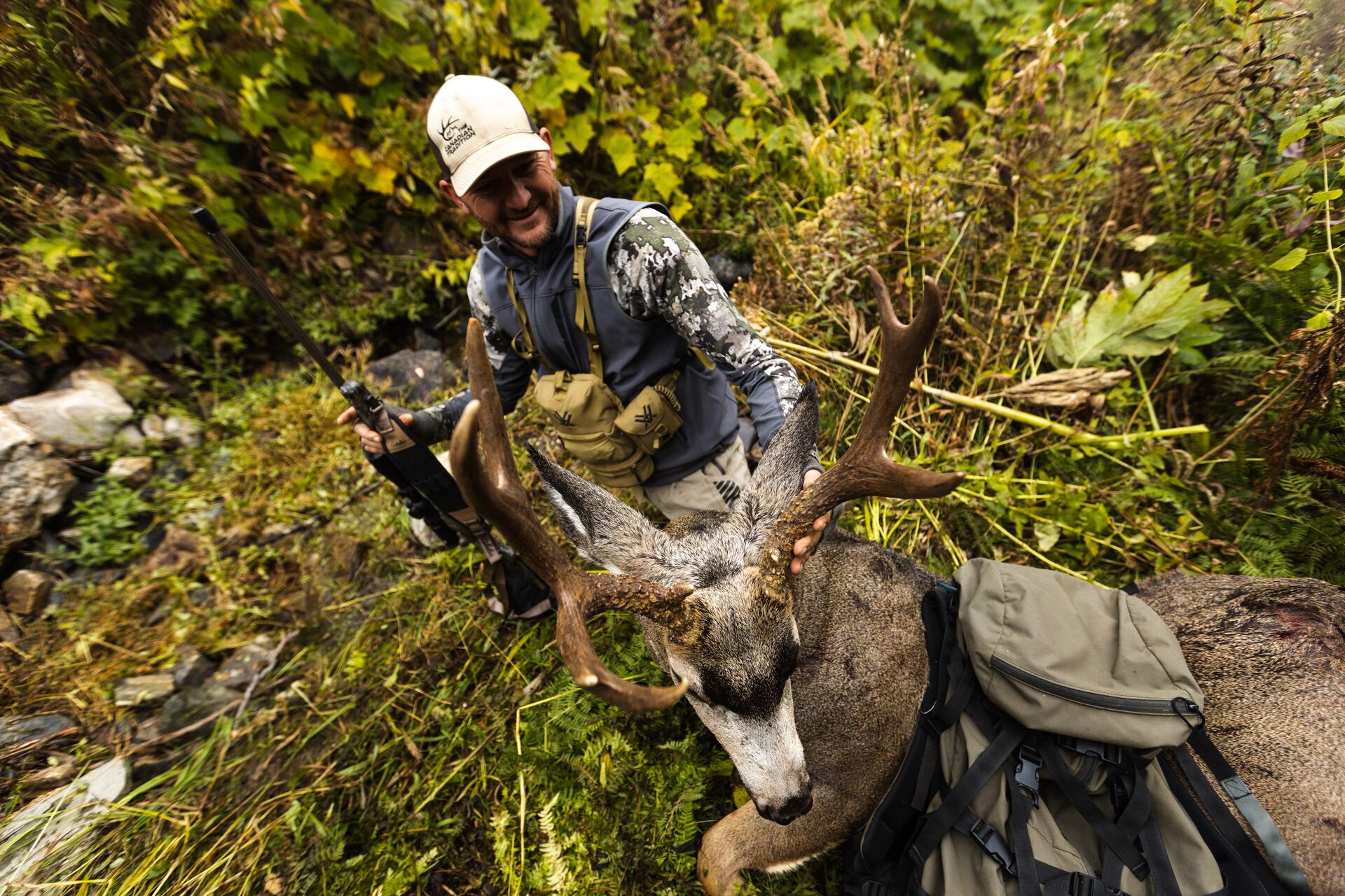 Hunter shows off mule deer after hunt in the woods, California hunting license cost.
