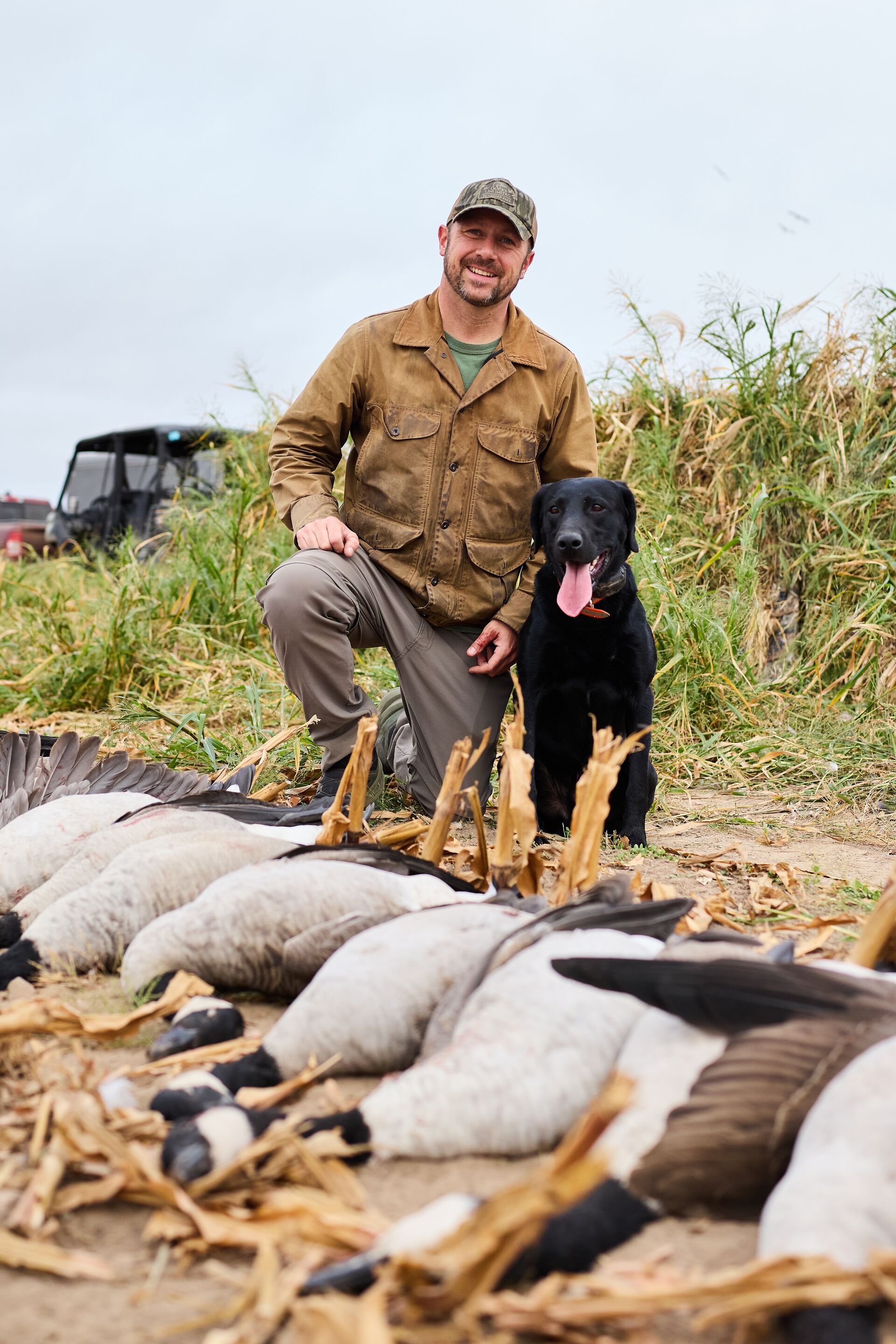 Hunter with dog and geese after hunt. 