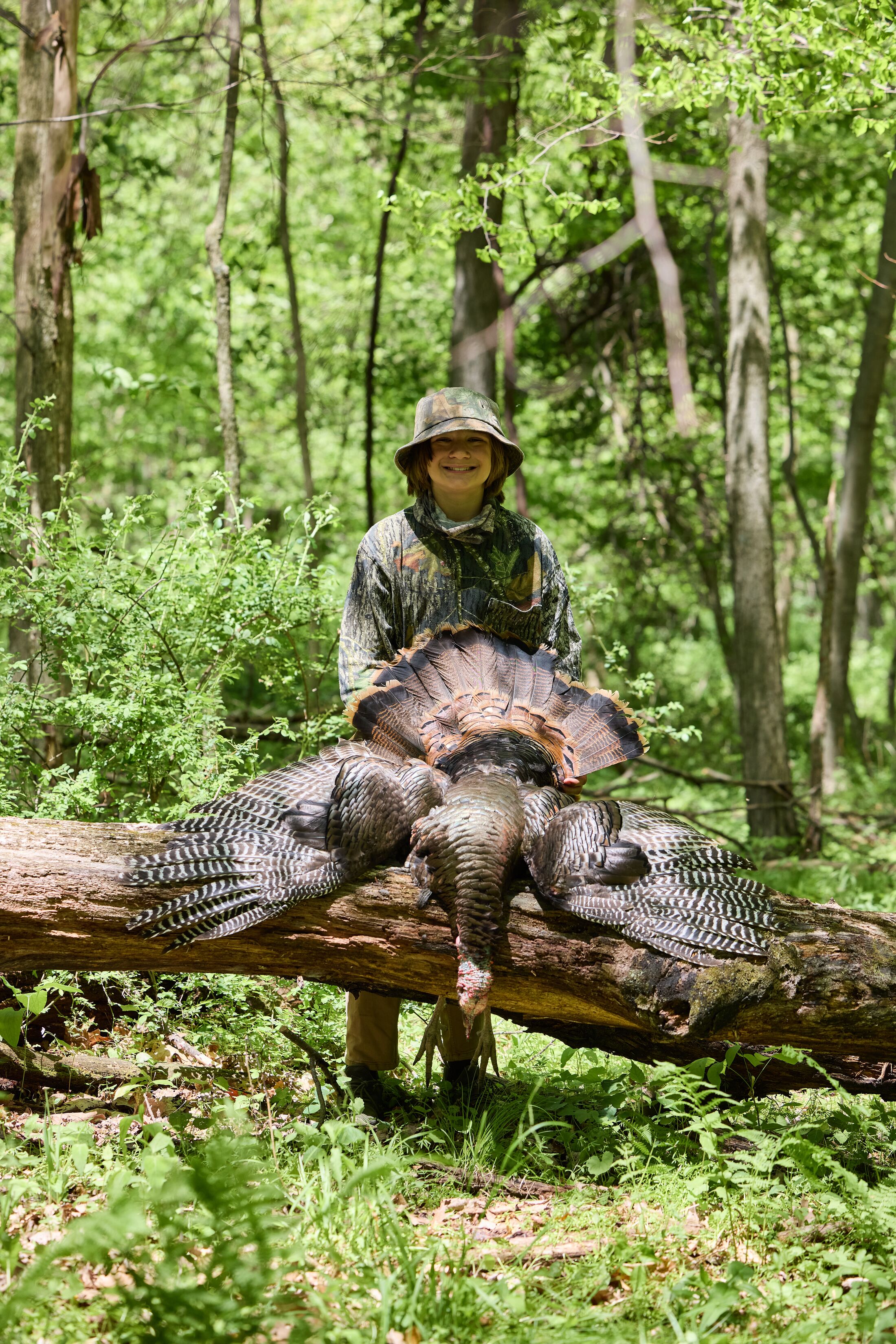 Smiling boy in camo with turkey after hunt, Wisconsin hunting license costs concept. 