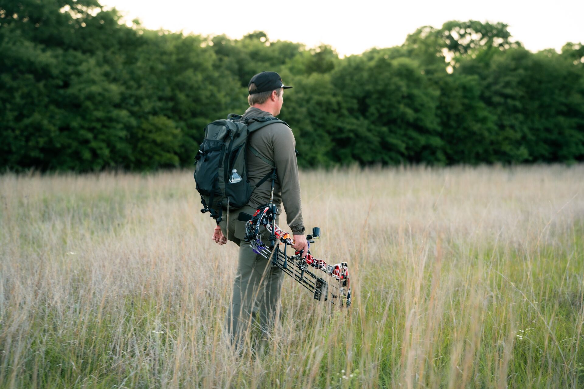 Hunter with backpack and bow in field, get a Georgia hunting license concept. 