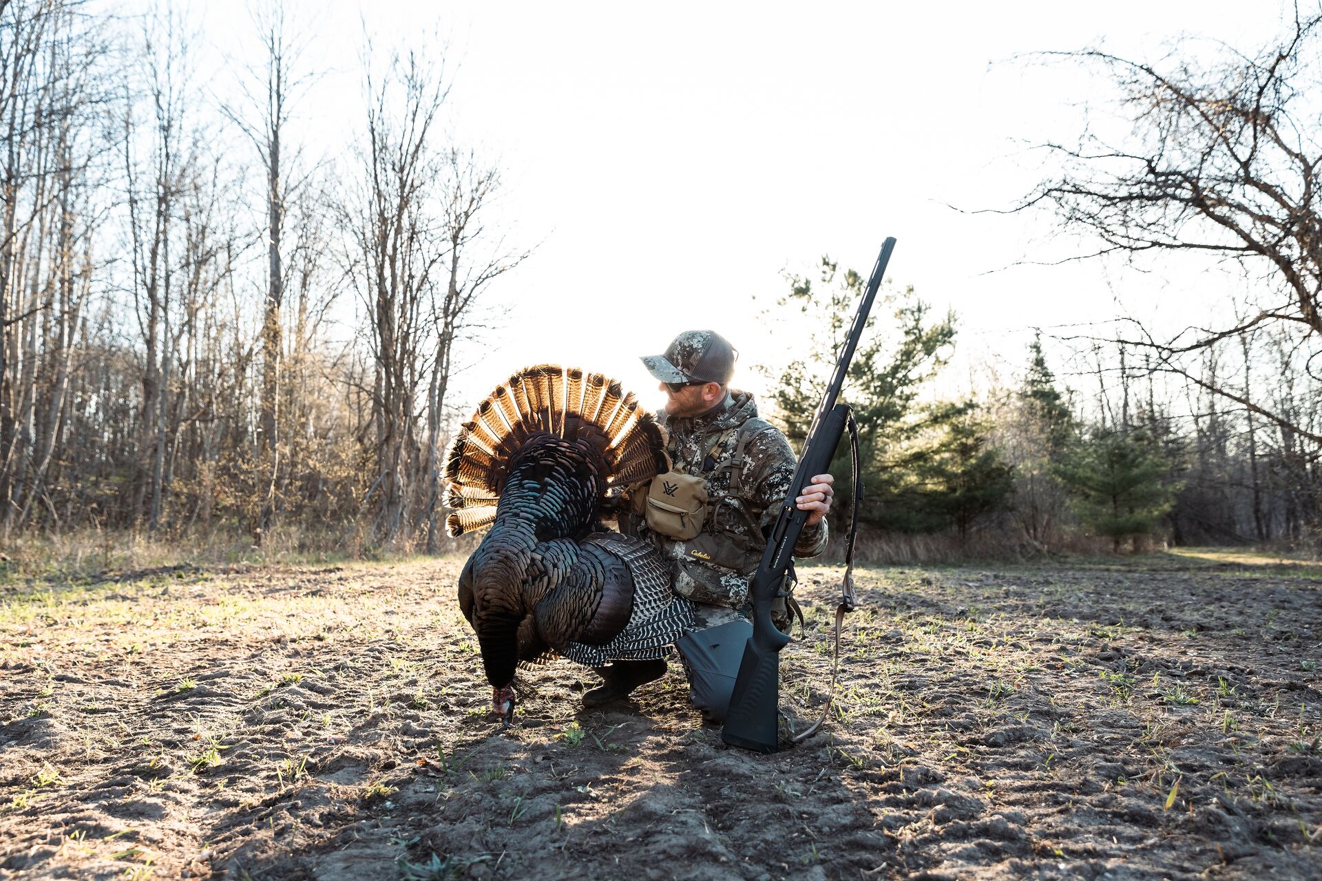 Hunter kneels with turkey after hunt, how much does it cost to get an Oklahoma hunting license concept. 