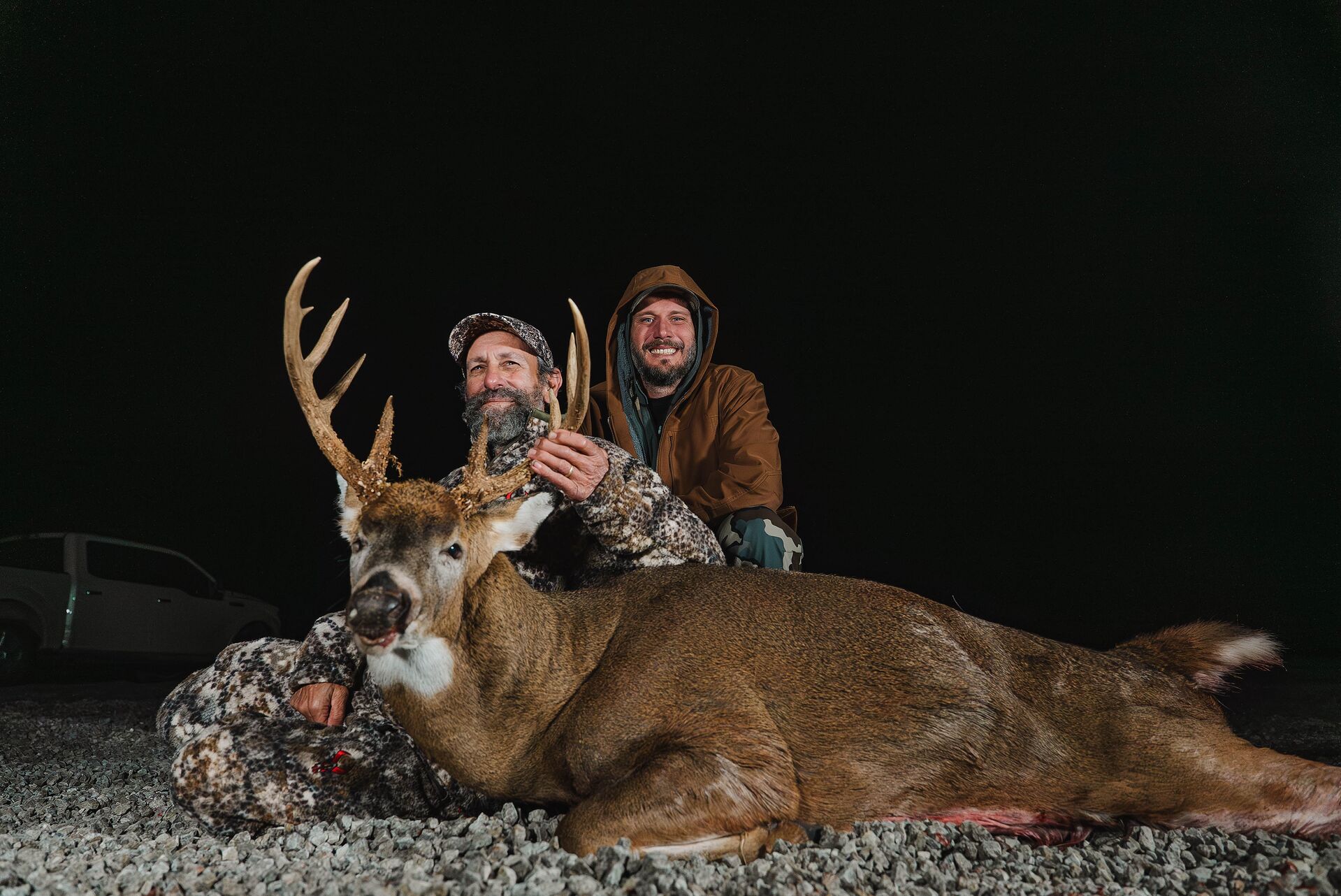 Two hunters show off deer after hunt, Oklahoma hunting license costs concept. 