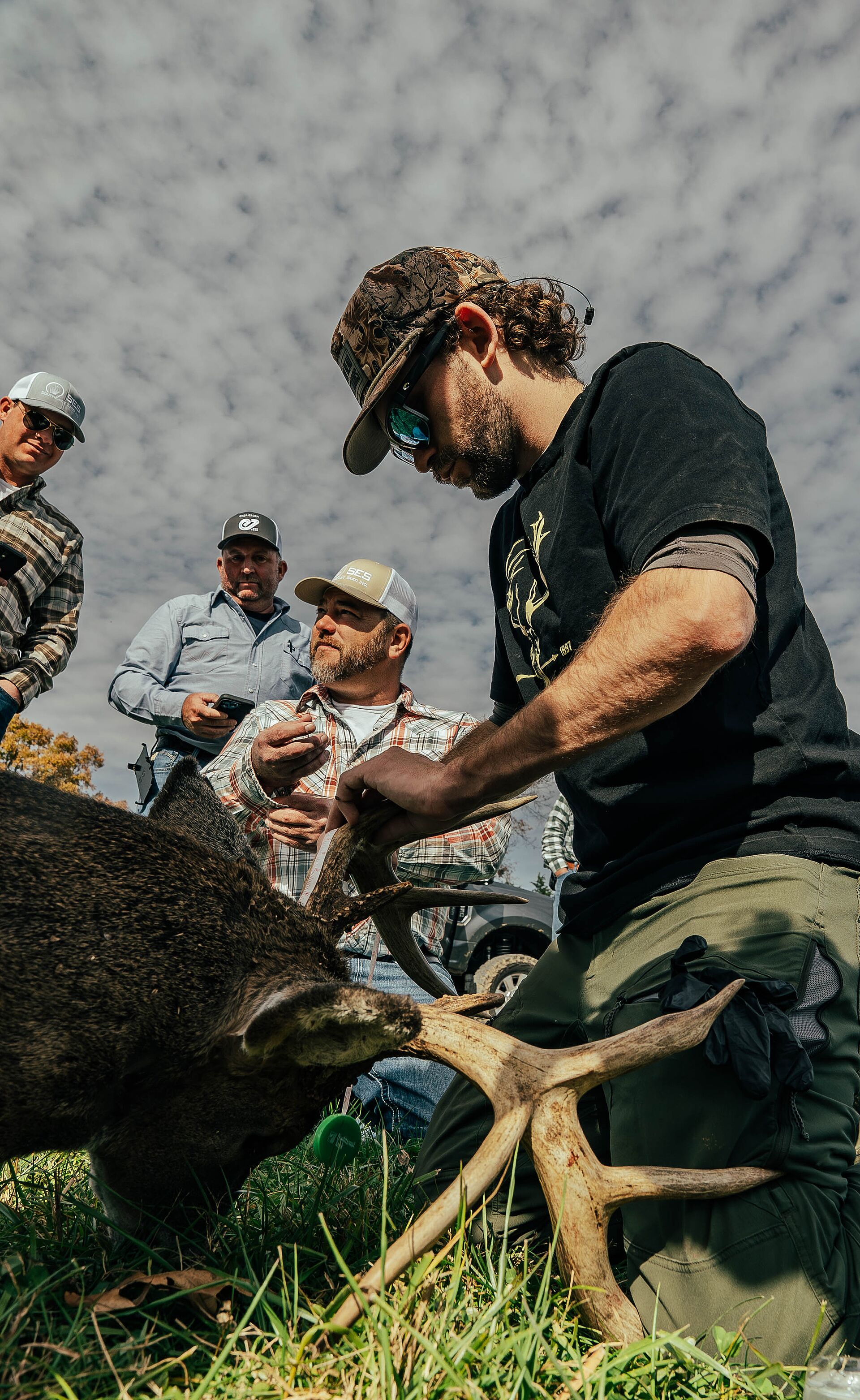 Hunter kneeling with buck deer after hunt.