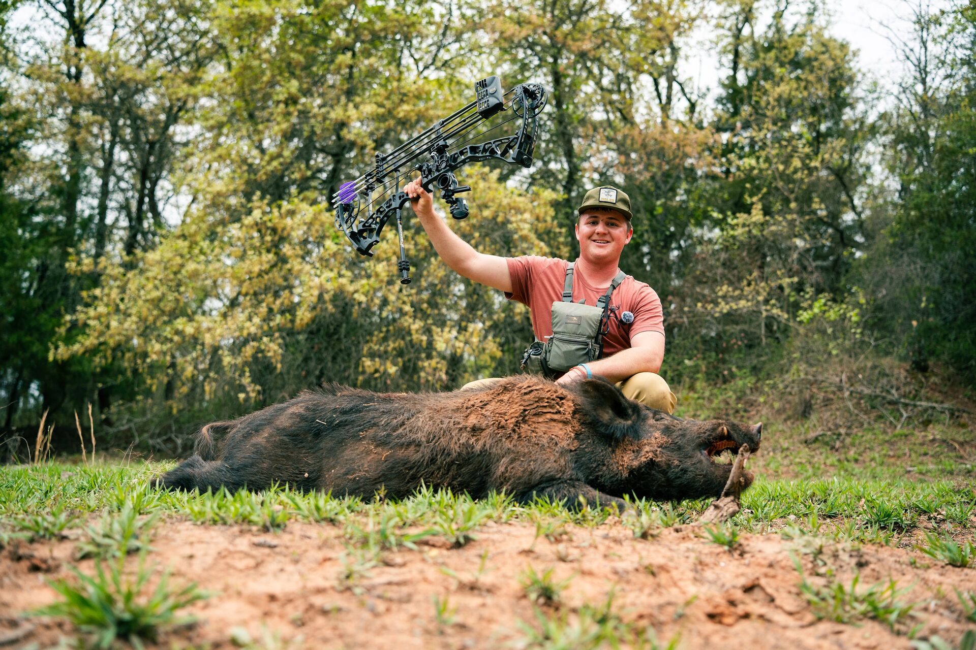 Young hunter raises bow with hog after hunt, how much does an Arizona hunting license cost concept.