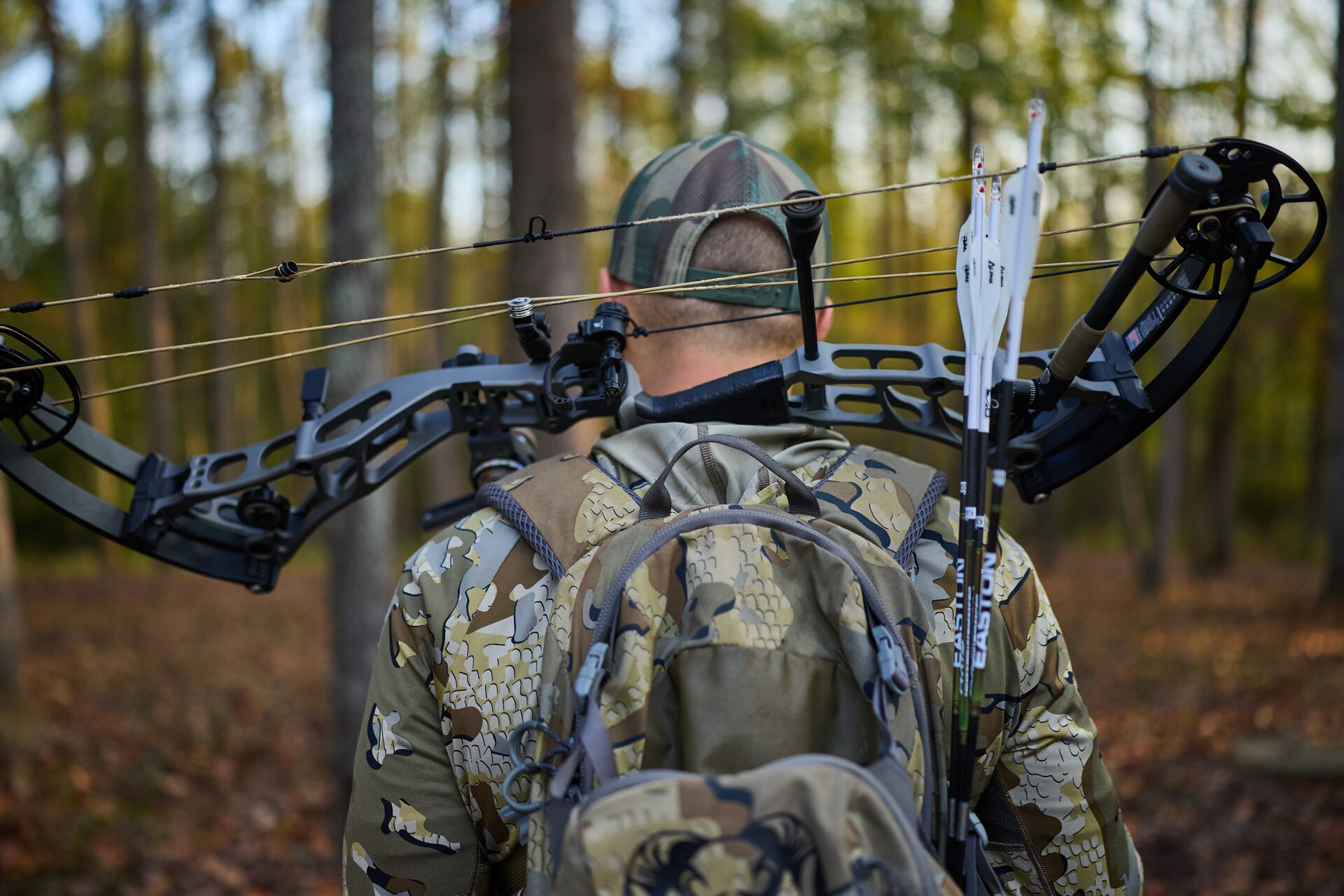 Back view of hunter carrying bow across shoulders, Mississippi hunting license cost concept.