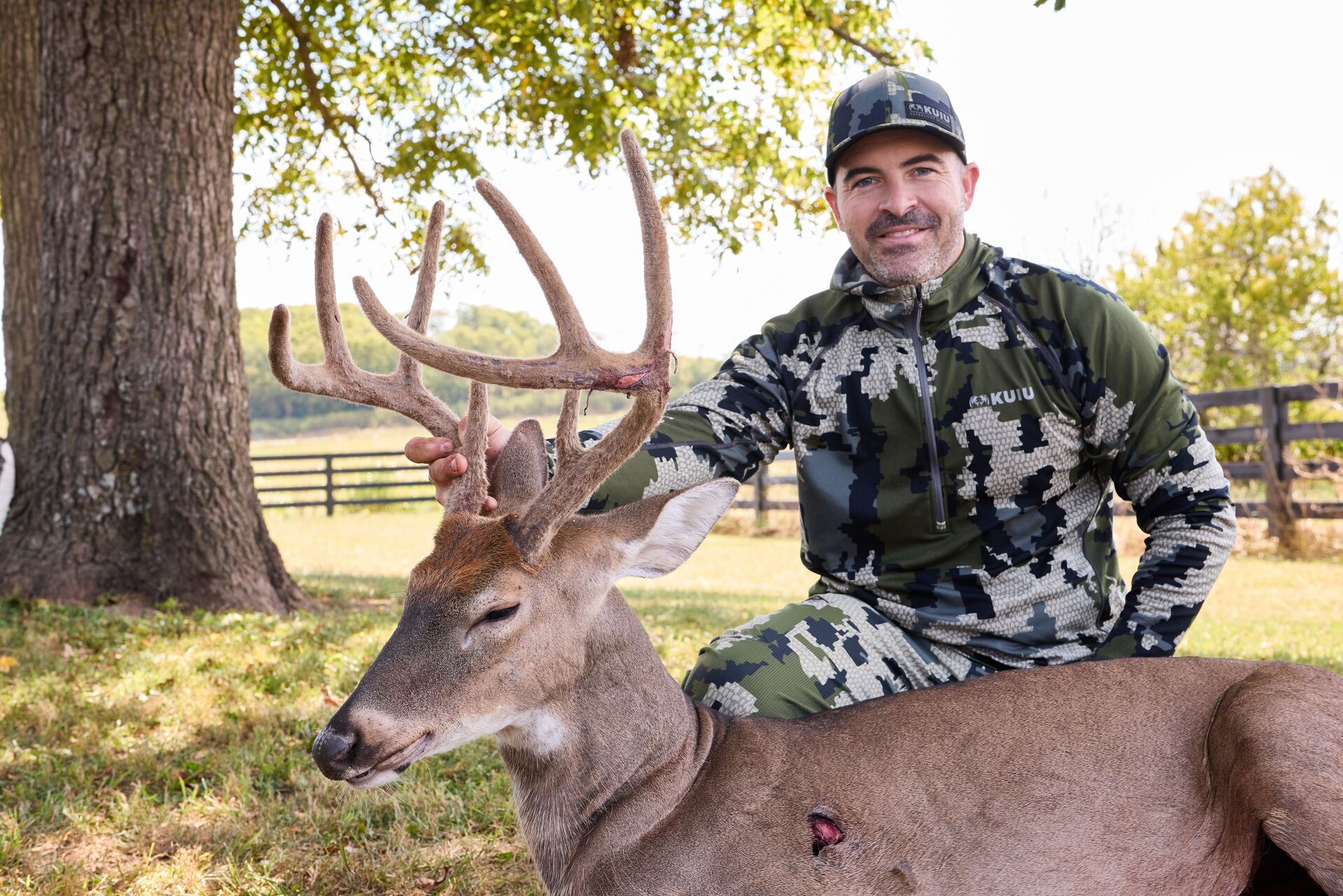 Hunter smiles with buck deer on the ground after hunt, Mississippi hunting license concept.