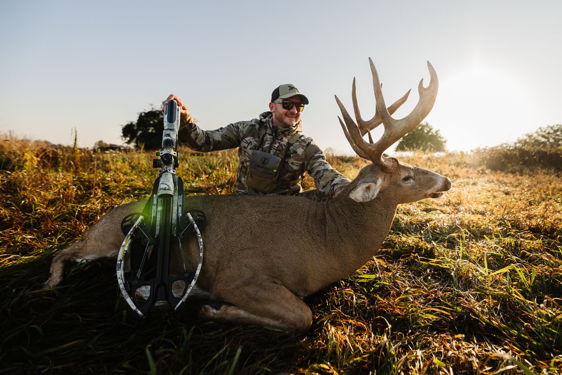 Hunter with bow and buck deer on ground after hunt, Mississippi hunting license cost concept.