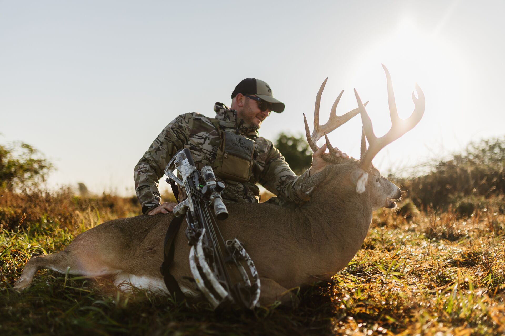 Hunter sits with bow and buck deer on the ground, how much does a Washington hunting license cost concept. 