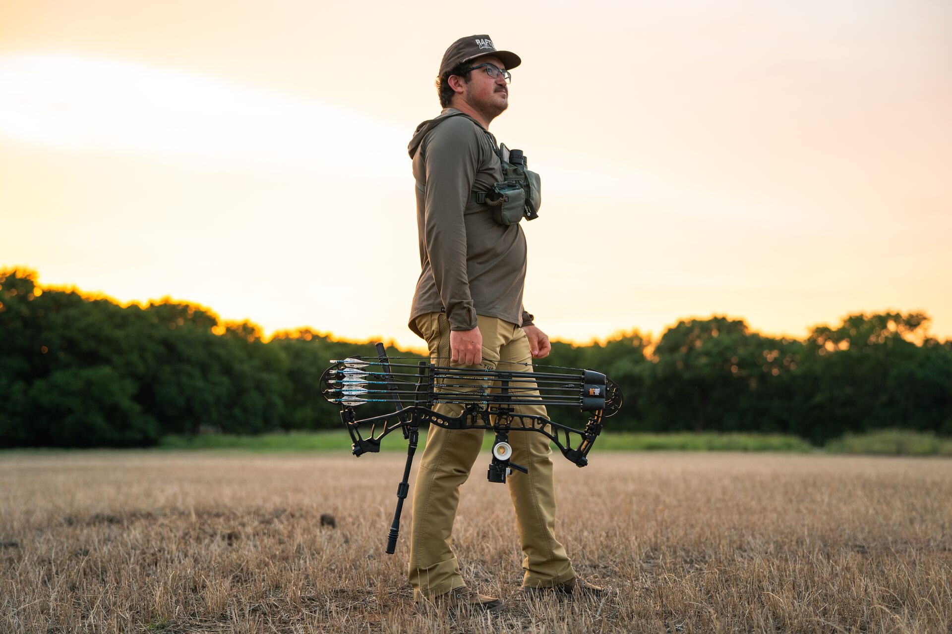 Hunter stands in field with bow, Kentucky hunting license concept. 