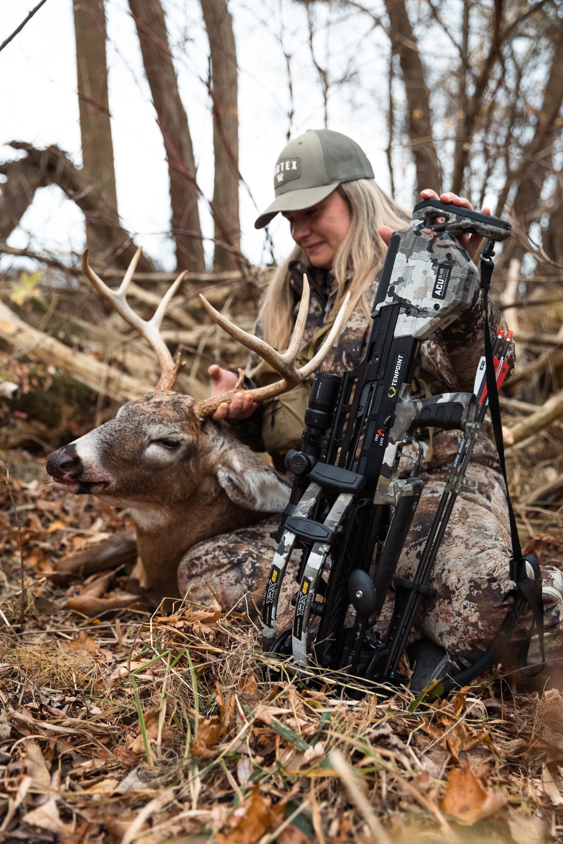 Female hunter with buck deer and bow on the ground after hunt, hunter safety course concept.