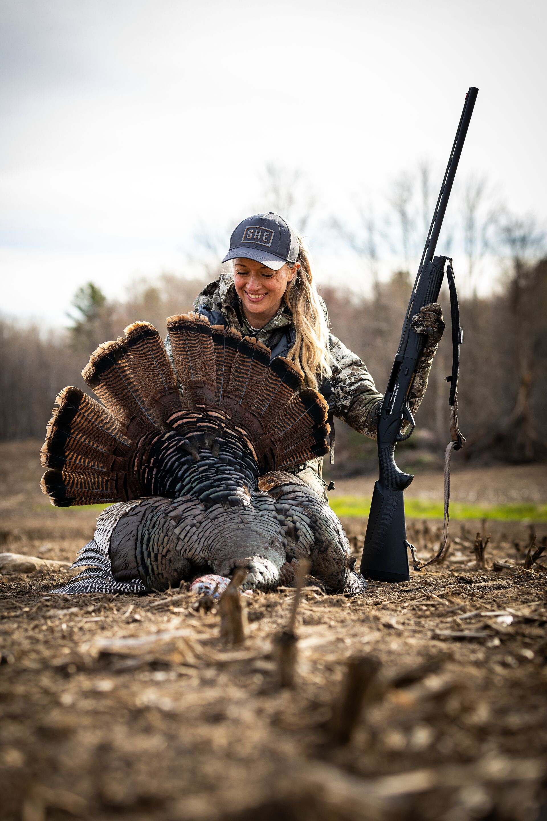 Female hunter smiles with turkey after hunt, take a hunter safety course concept.