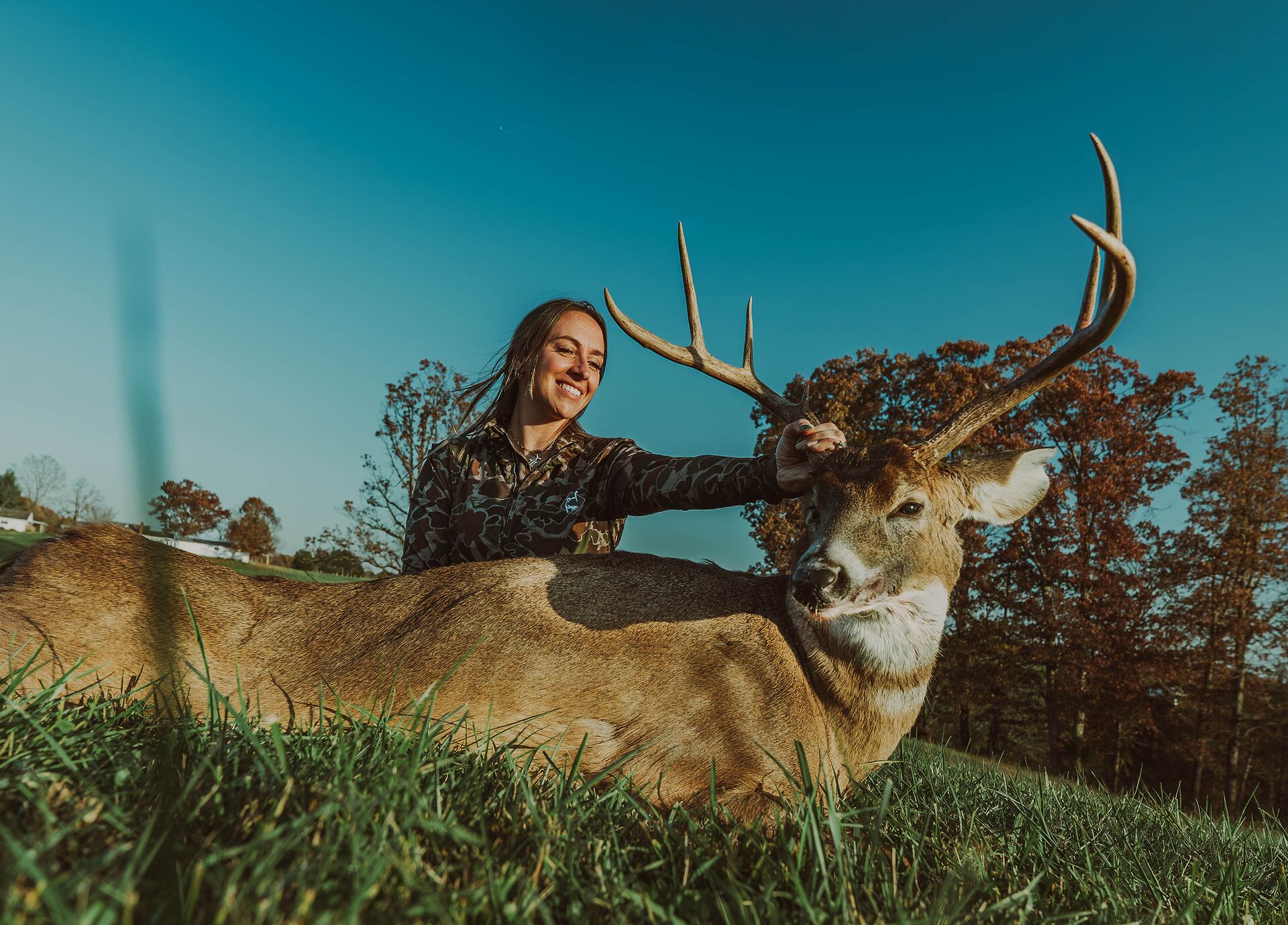 Female hunter posing with deer after hunt, get a Wisconsin hunting license concept.