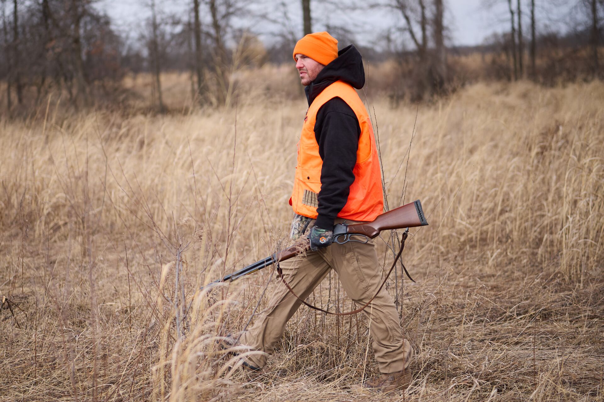 Hunter in blaze orange vest and hat walks with firearm, get a NV hunting license concept. 