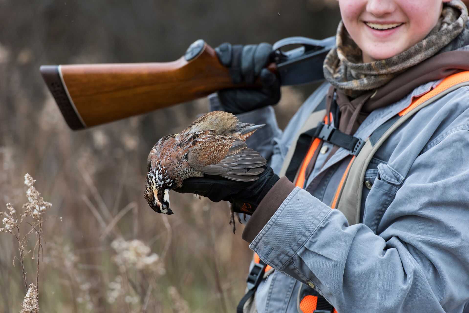 Girl with shotgun and bird after hunt, youth hunting license concept.